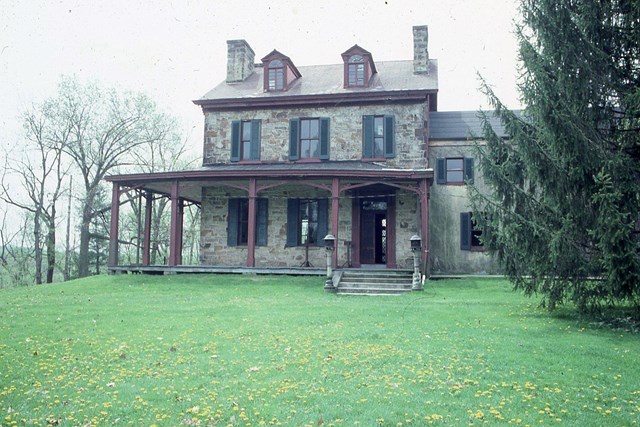 spring green lawn and trees surrounding old stone house