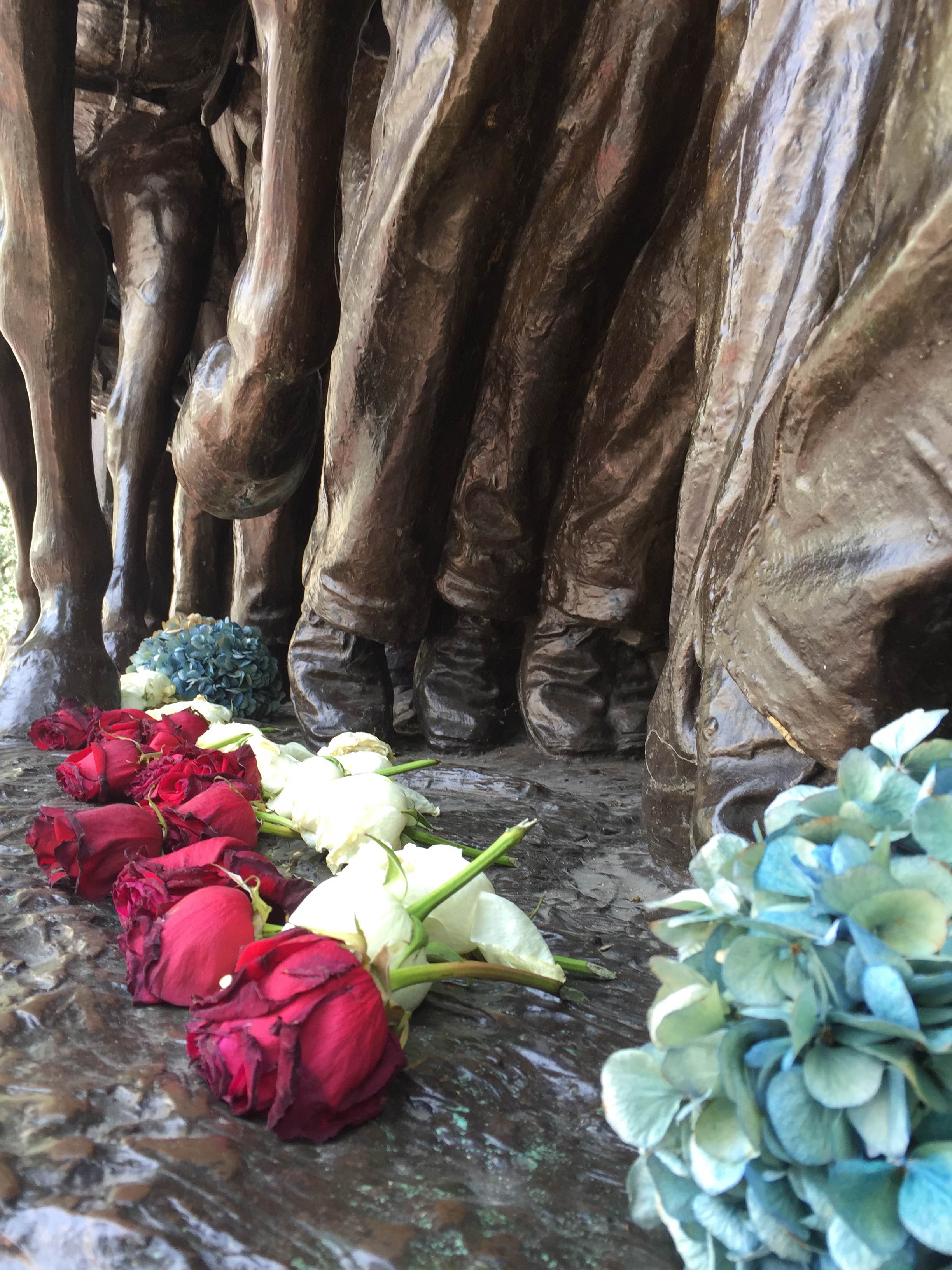 A close up image of flowers laid at the feet of the soldiers on the Shaw Memorial