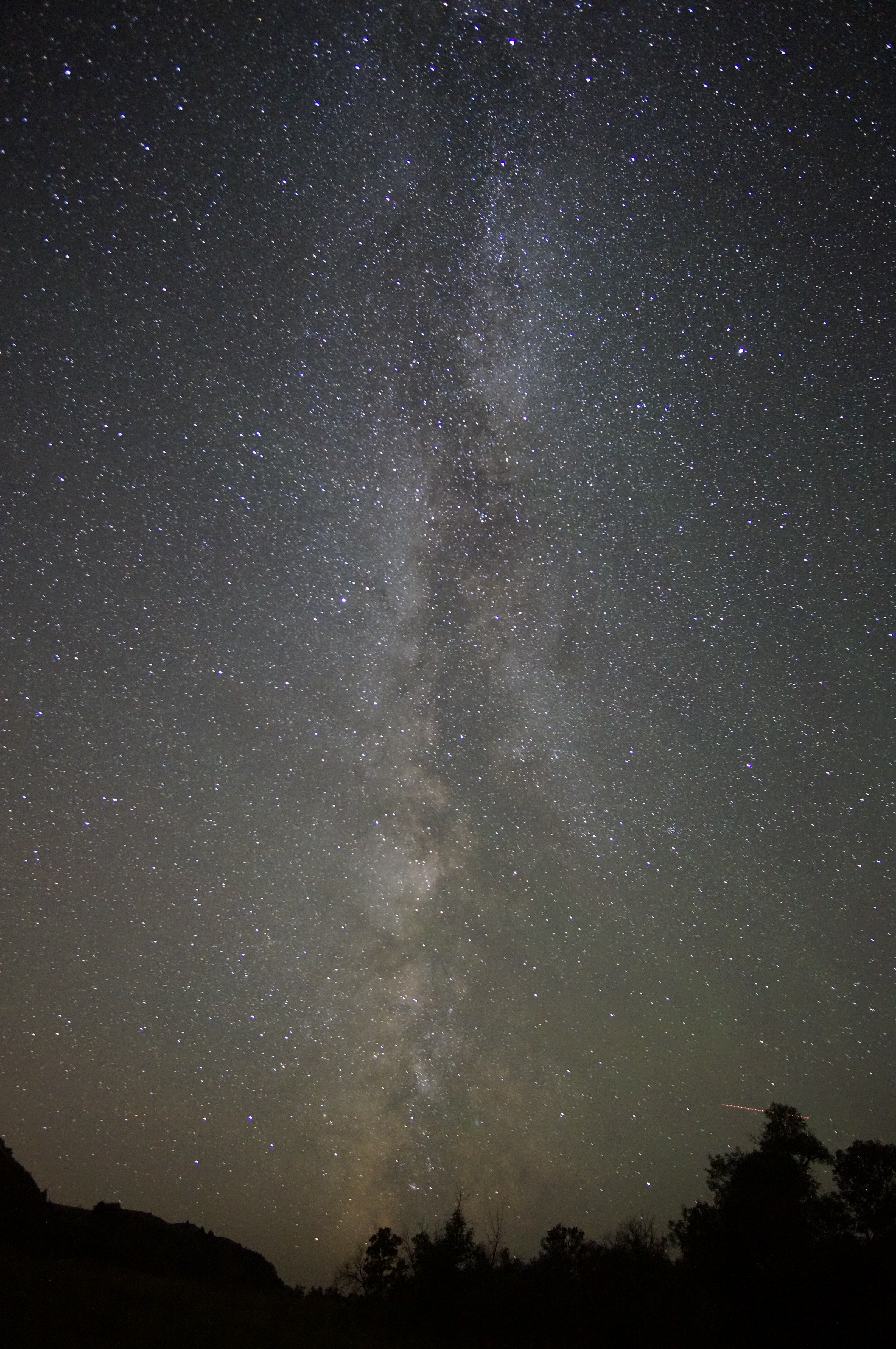 the swirling, dusty looking milky way runs vertically though a starry night sky