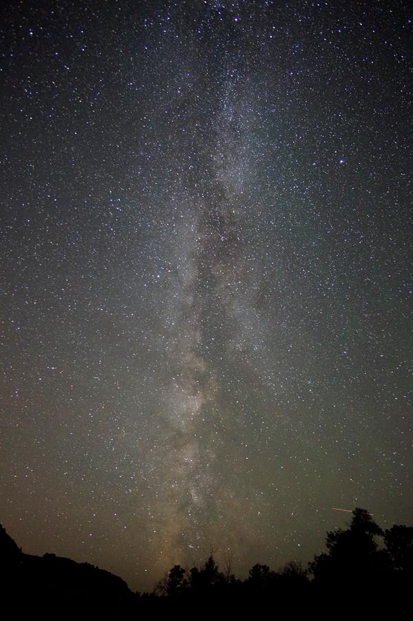 the swirling, dusty looking milky way runs vertically though a starry night sky