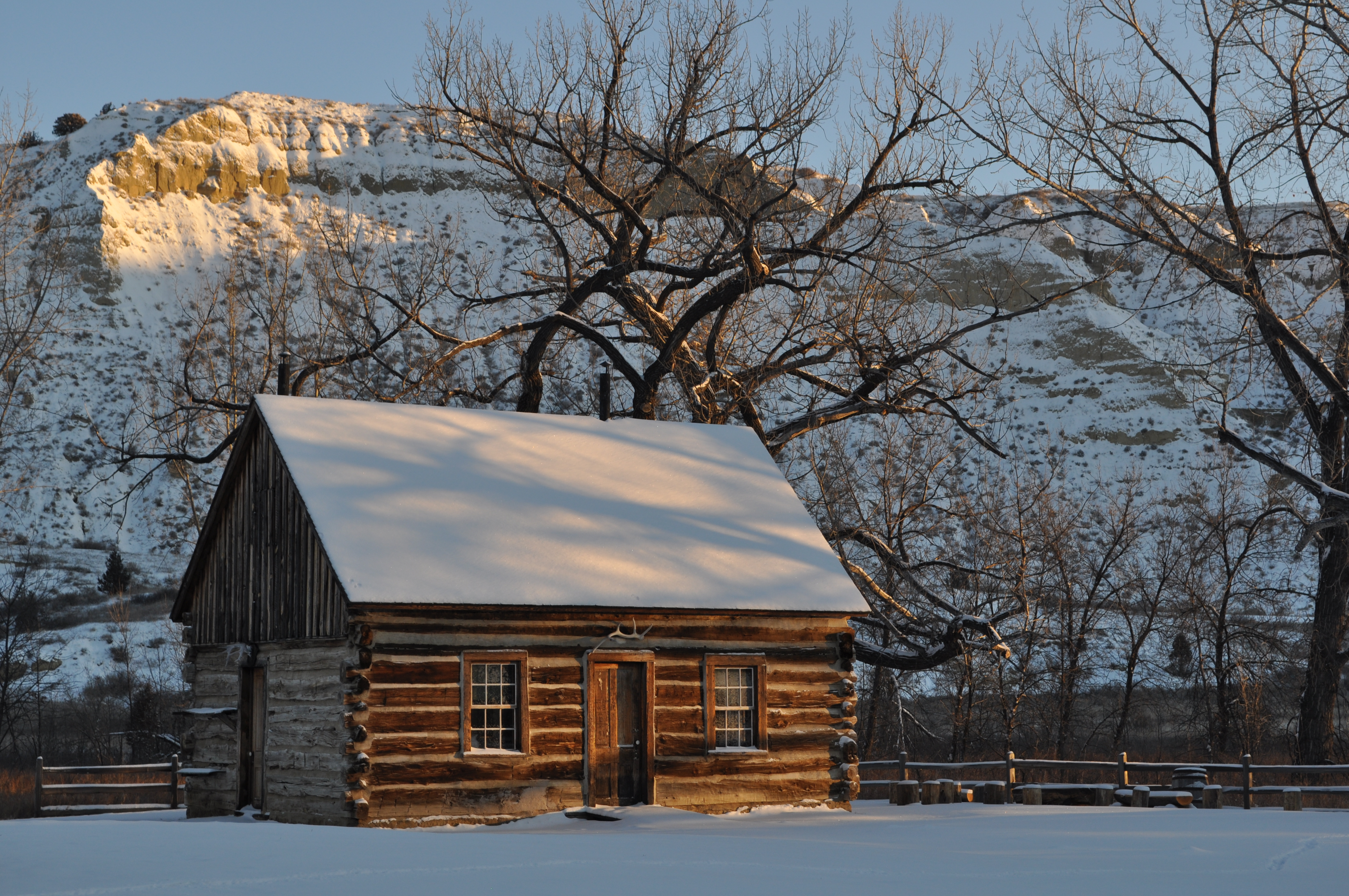 The rising sun casts light on Roosevelt's snow-covered cabin.