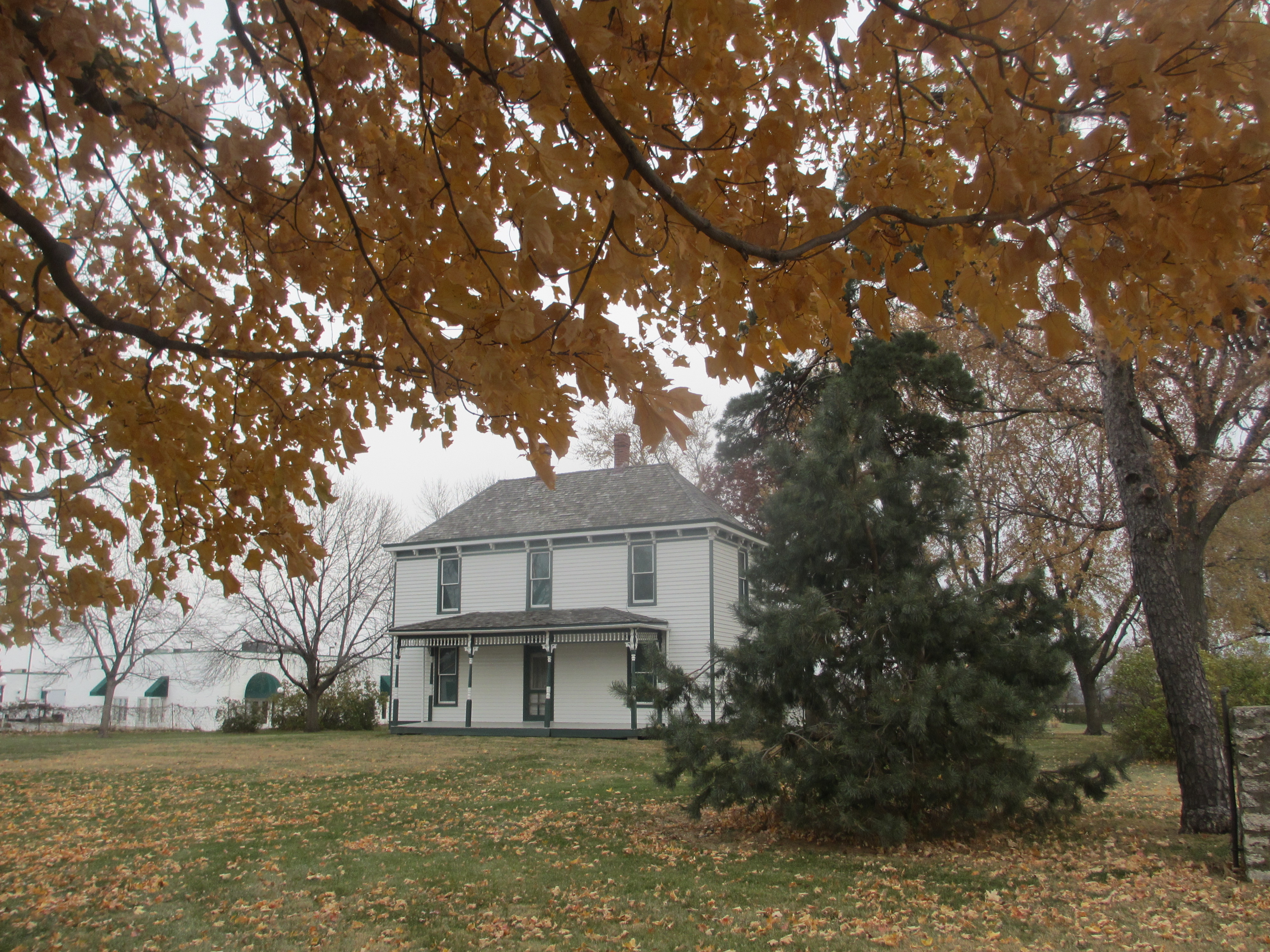The Truman Farm Home sits behind Autumn trees.