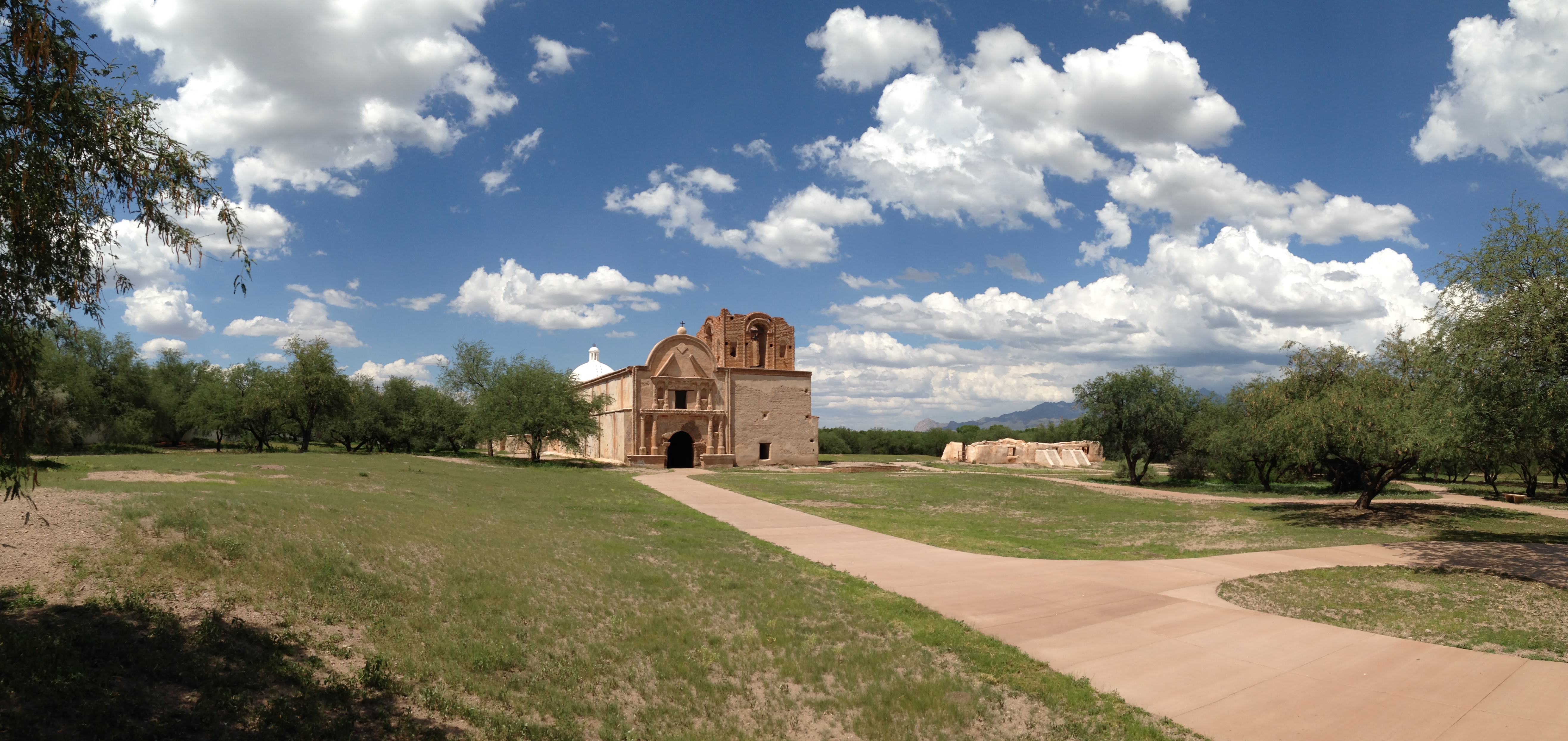 panorama of mission church with green grass and clouds