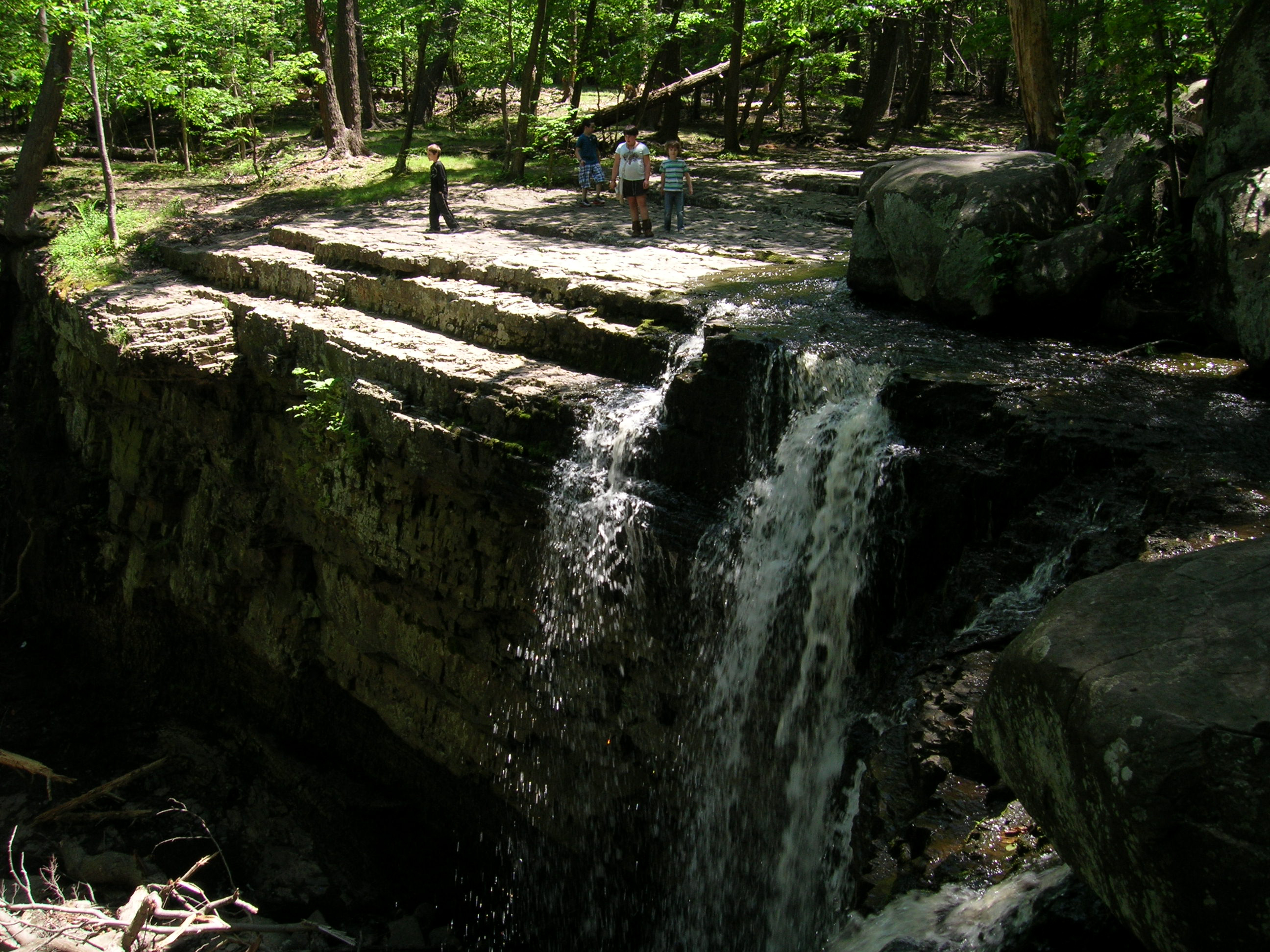 water falls over a layered stone cliff face