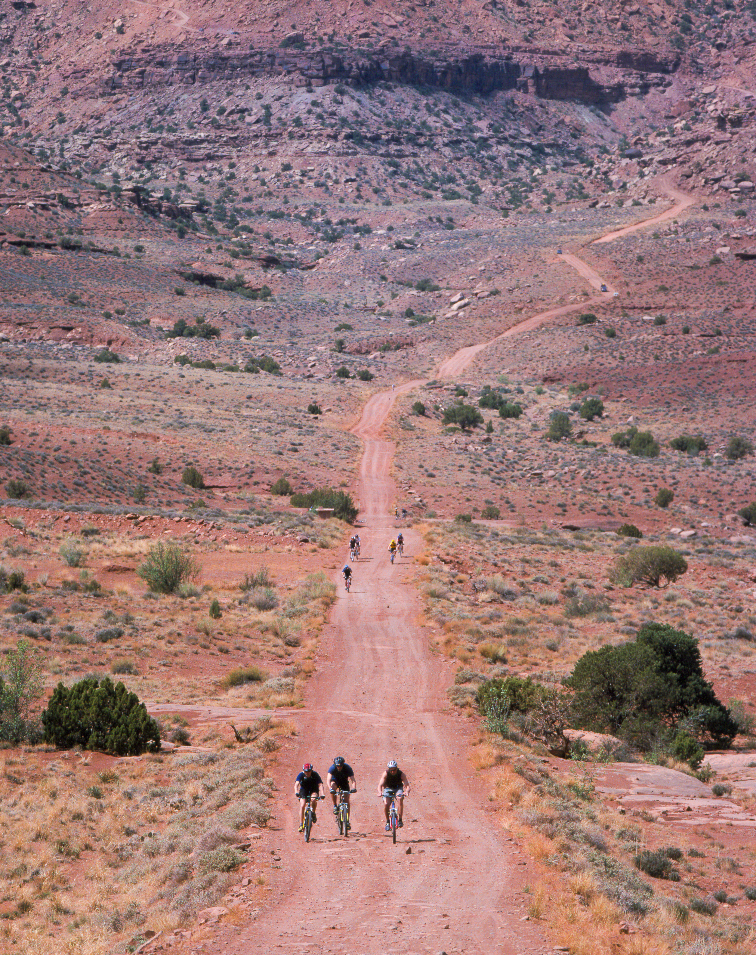 a long gravel road with cyclists on it