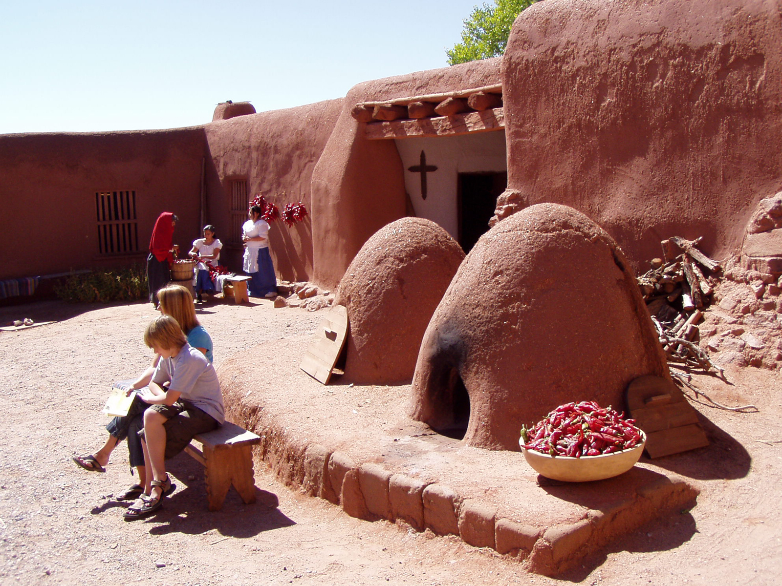 adobe buildings including two beehive-looking ovens with people in a courtyard