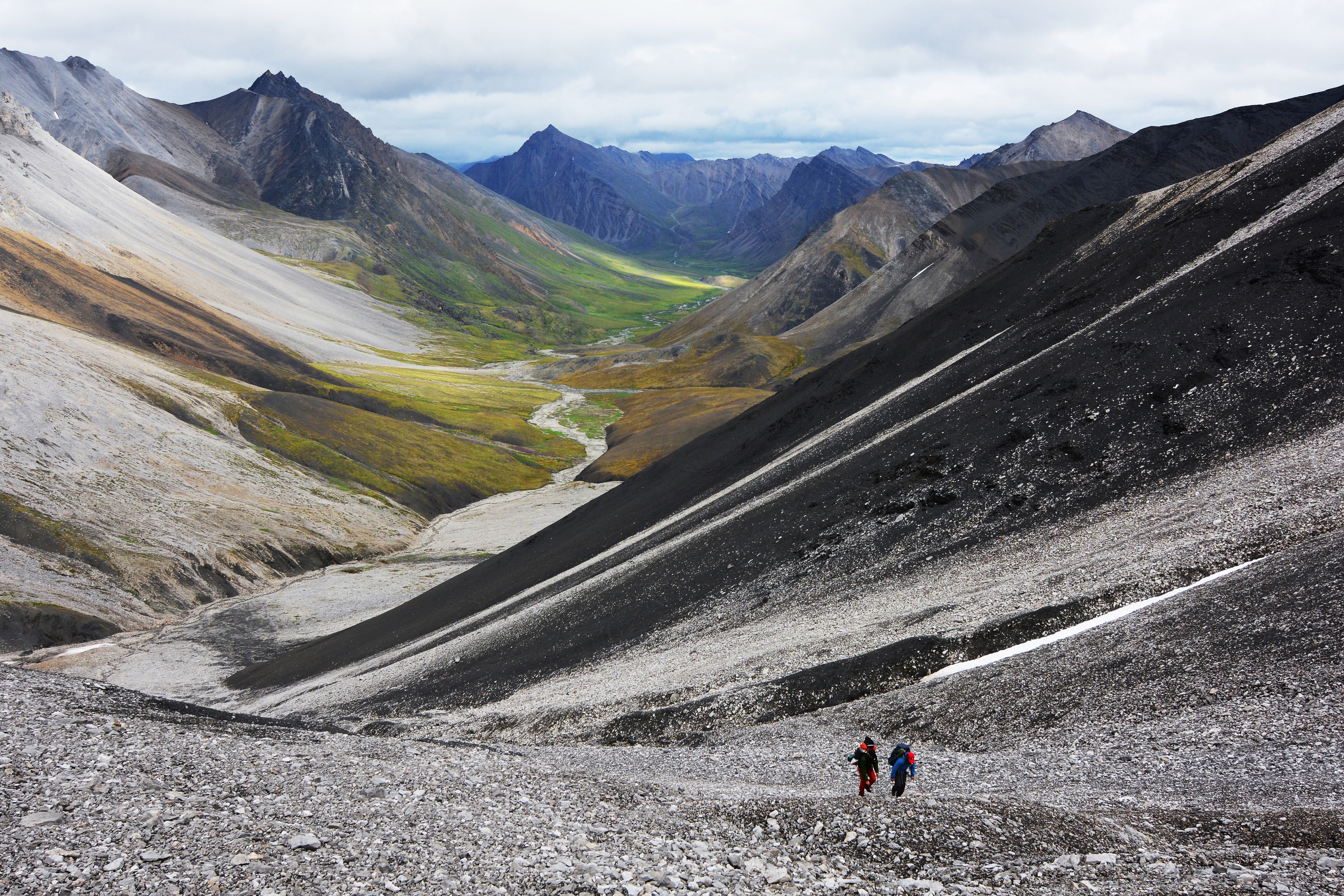 Two hikers climb up a mountain pass