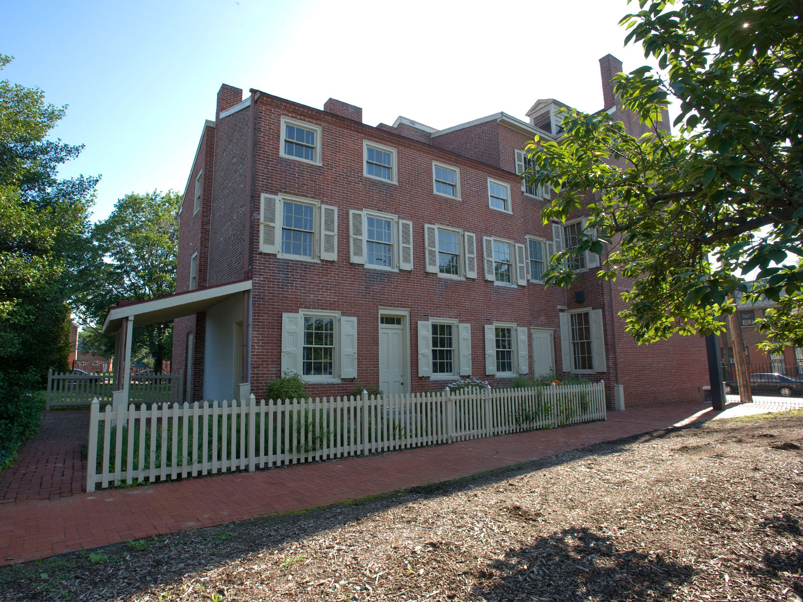 Color photo of a rectangular three story brick home with rows of windows on each floor.
