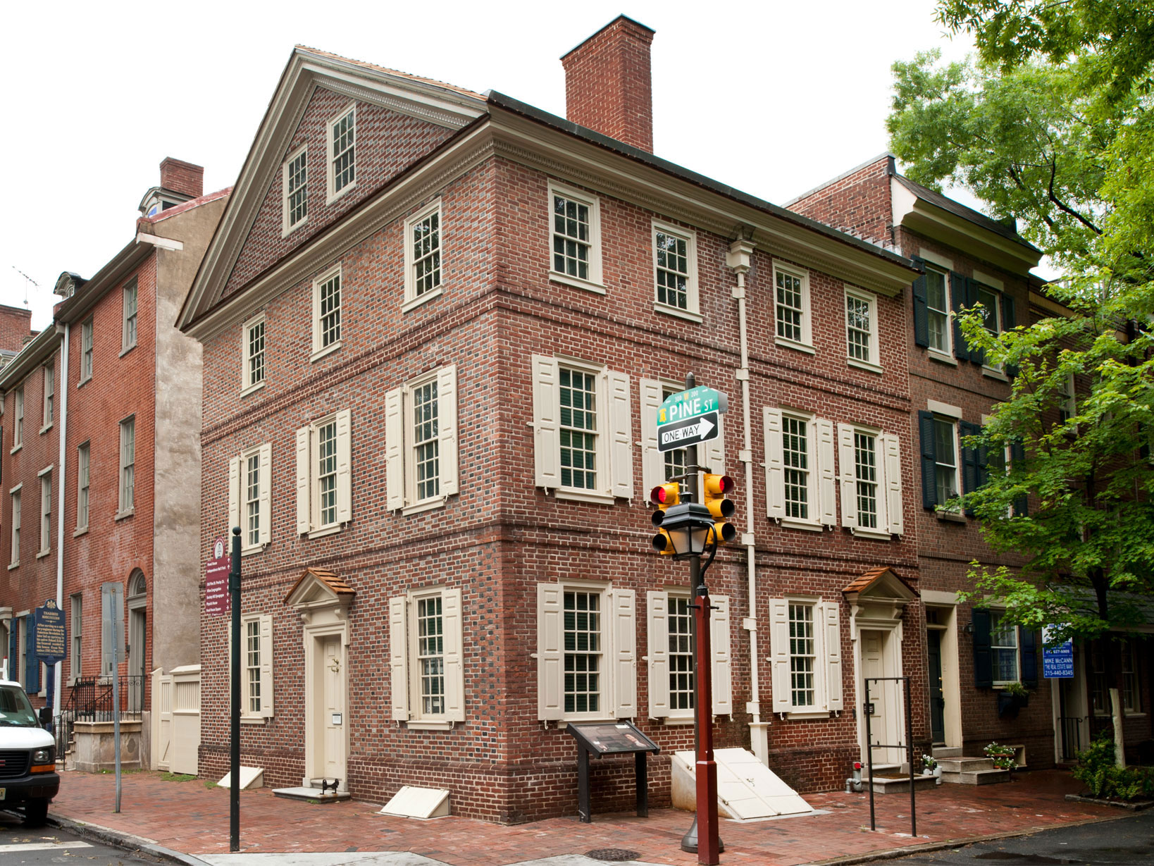 Color photo showing a three story brick rowhouse on a corner lot.