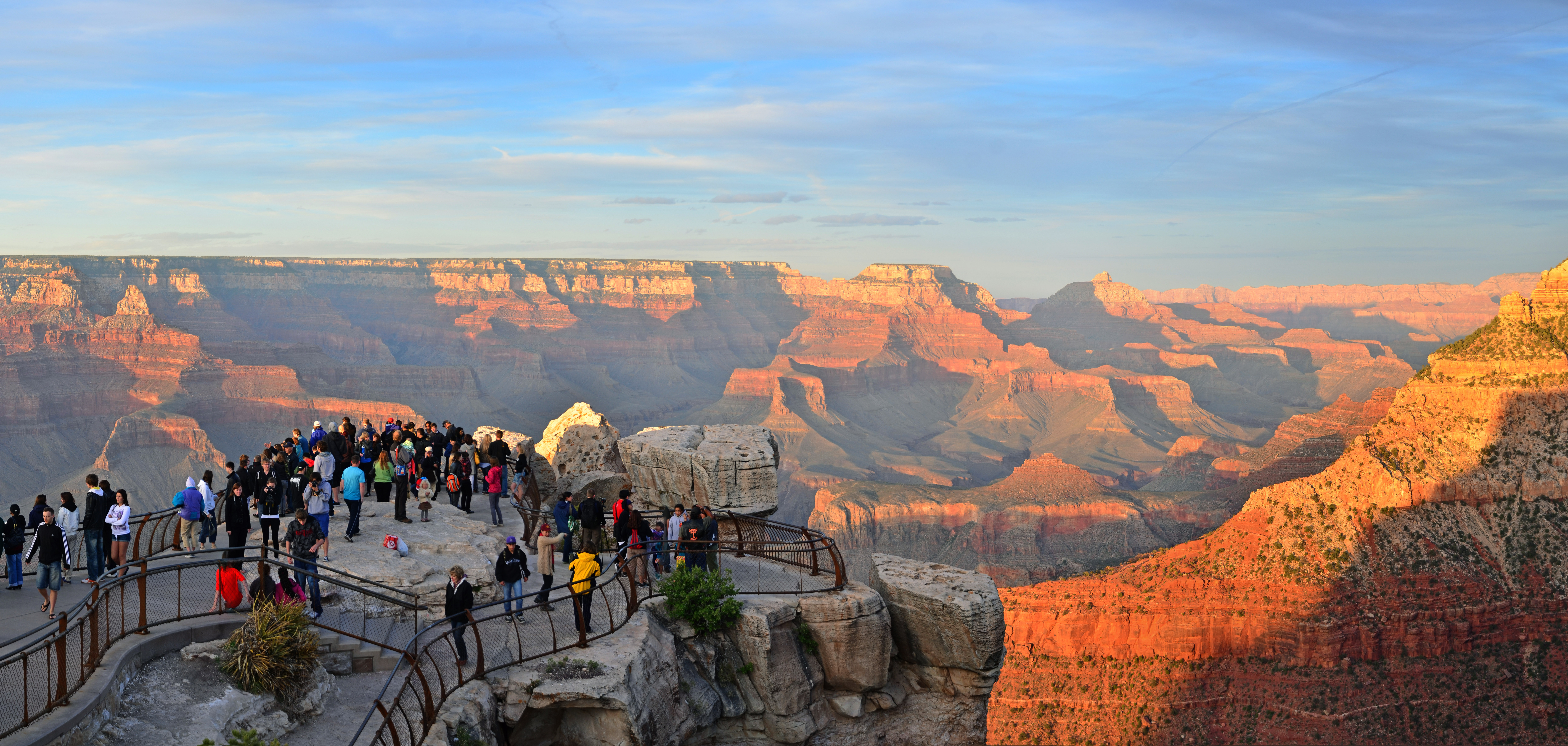 The canyon glows orange as people visit Mather Point, a rock outcropping that juts into Grand Canyon