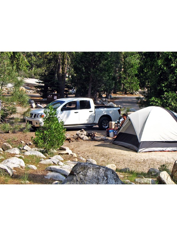 A tent in a flat area next to a vehicle