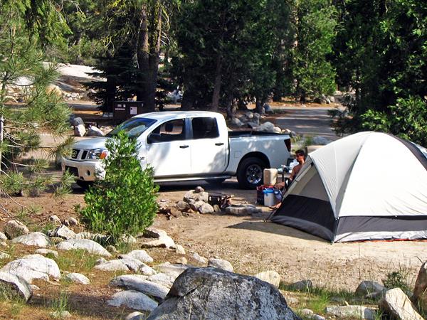 A tent in a flat area next to a vehicle