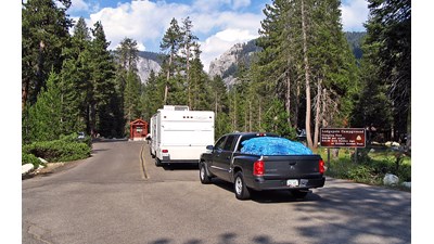 Vehicles near a kiosk in a forested canyon