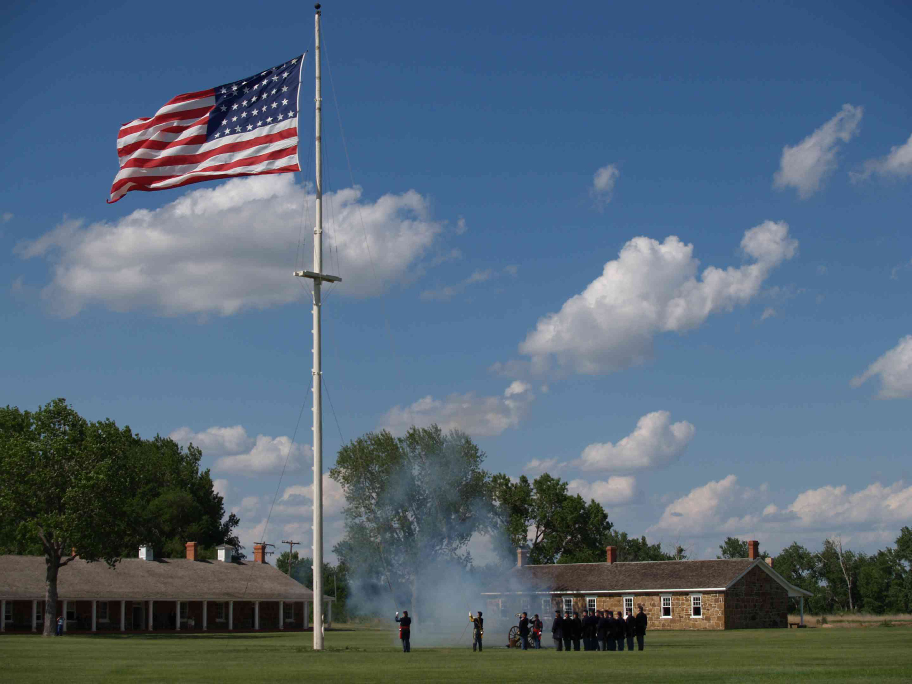 Men in 19th century U.S. Army uniforms lower an American flag.