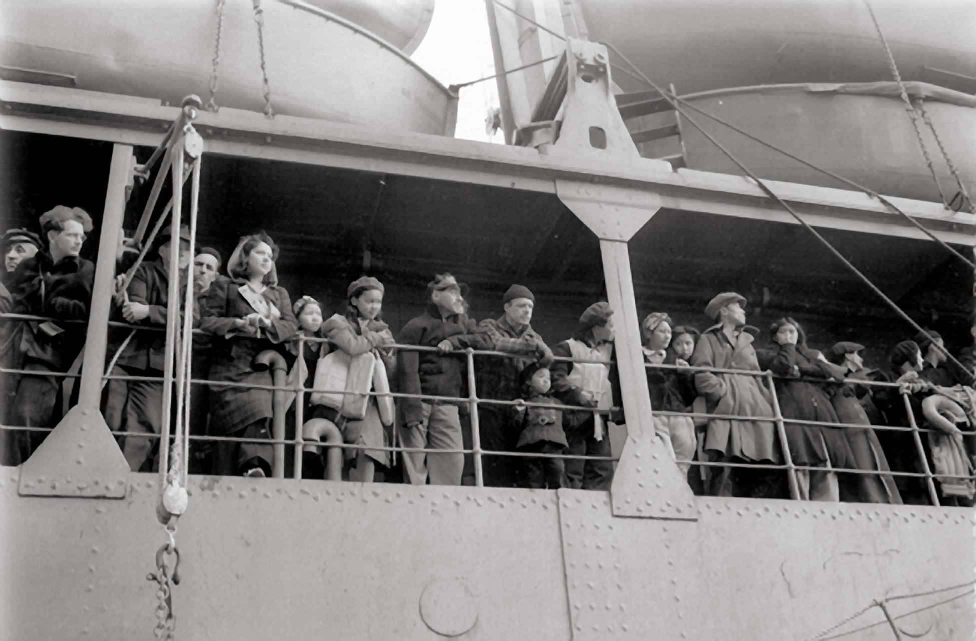 People crowd at the railing of a ship