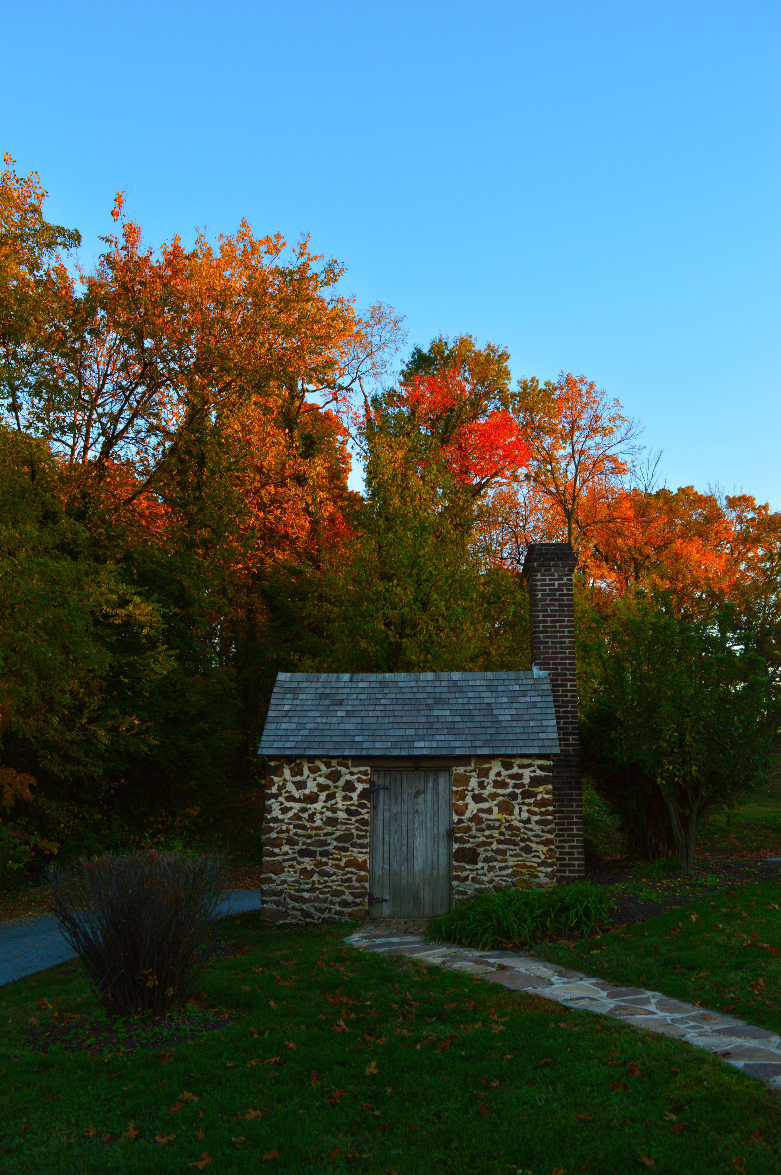 A tiny stone cabin surrounded by fall foliage