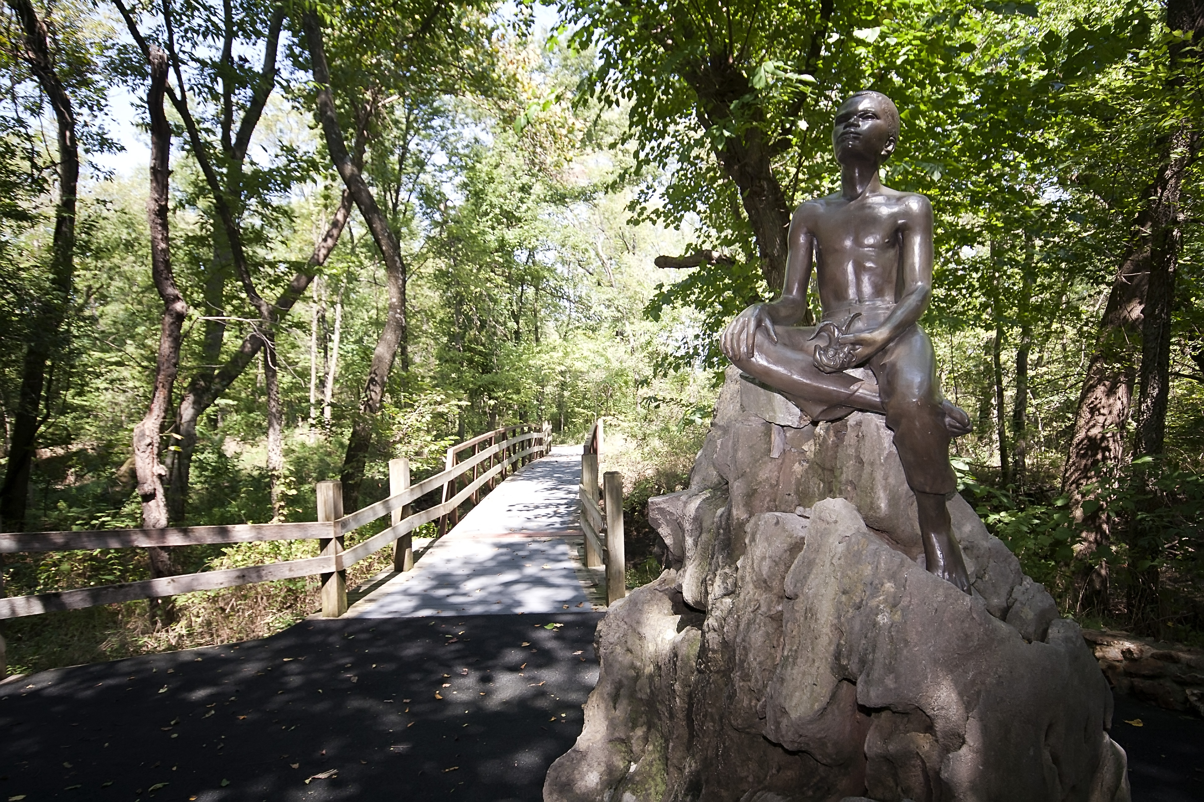 Bronze status of young George Washington Carver atop a large boulder, on the Carver trail.