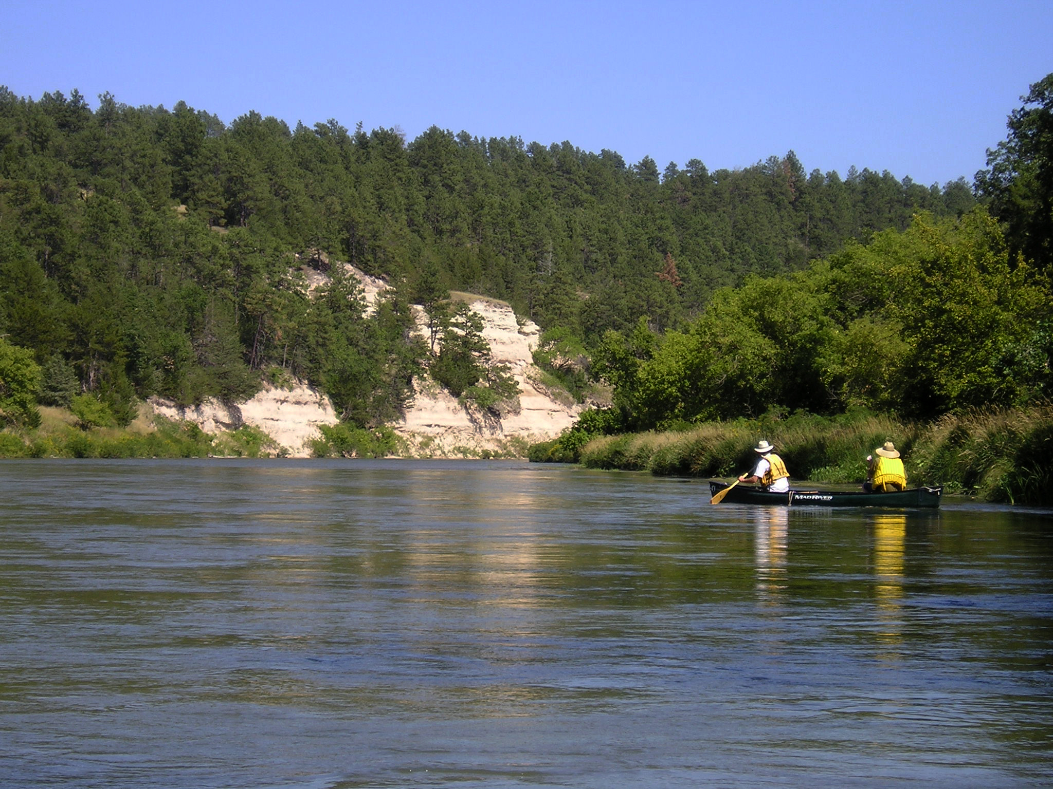 Two people in one canoe paddle along the bluffs of the Niobrara NSR.
