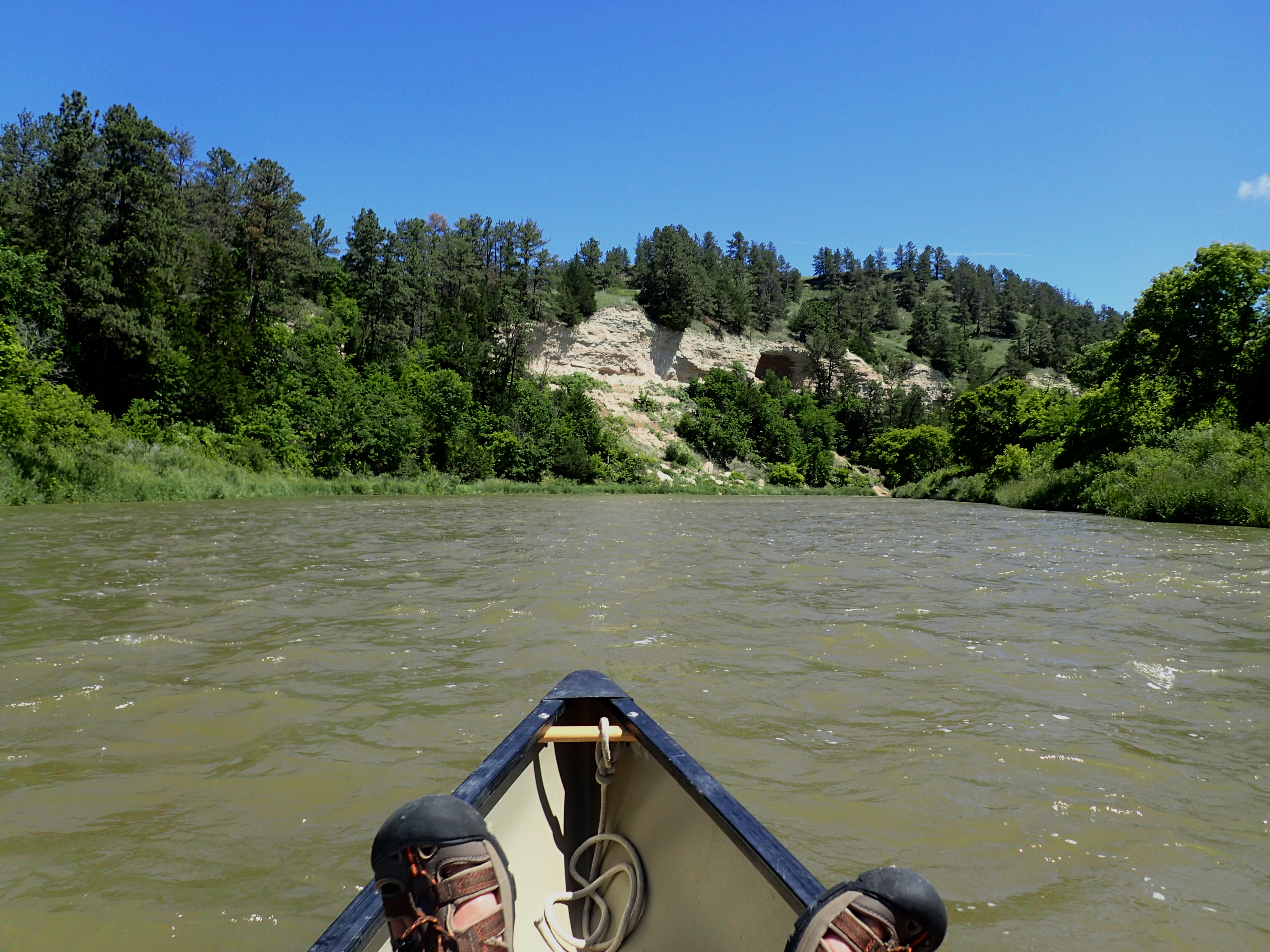 A view from a canoe, with the photographer's feet resting on the bow, of the Niobrara NSR.