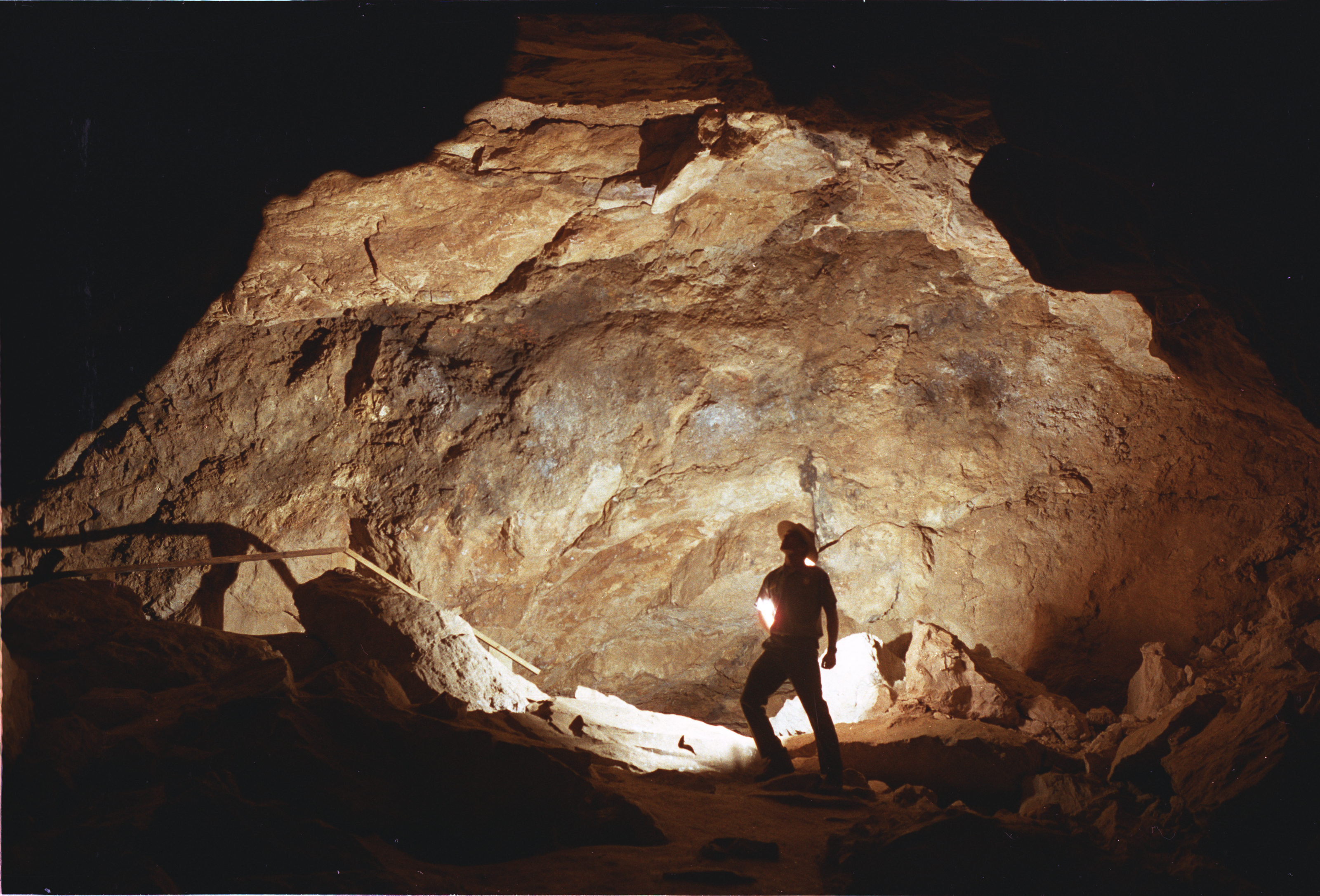 A park ranger stands as a silhouette in a large room in Jewel Cave.