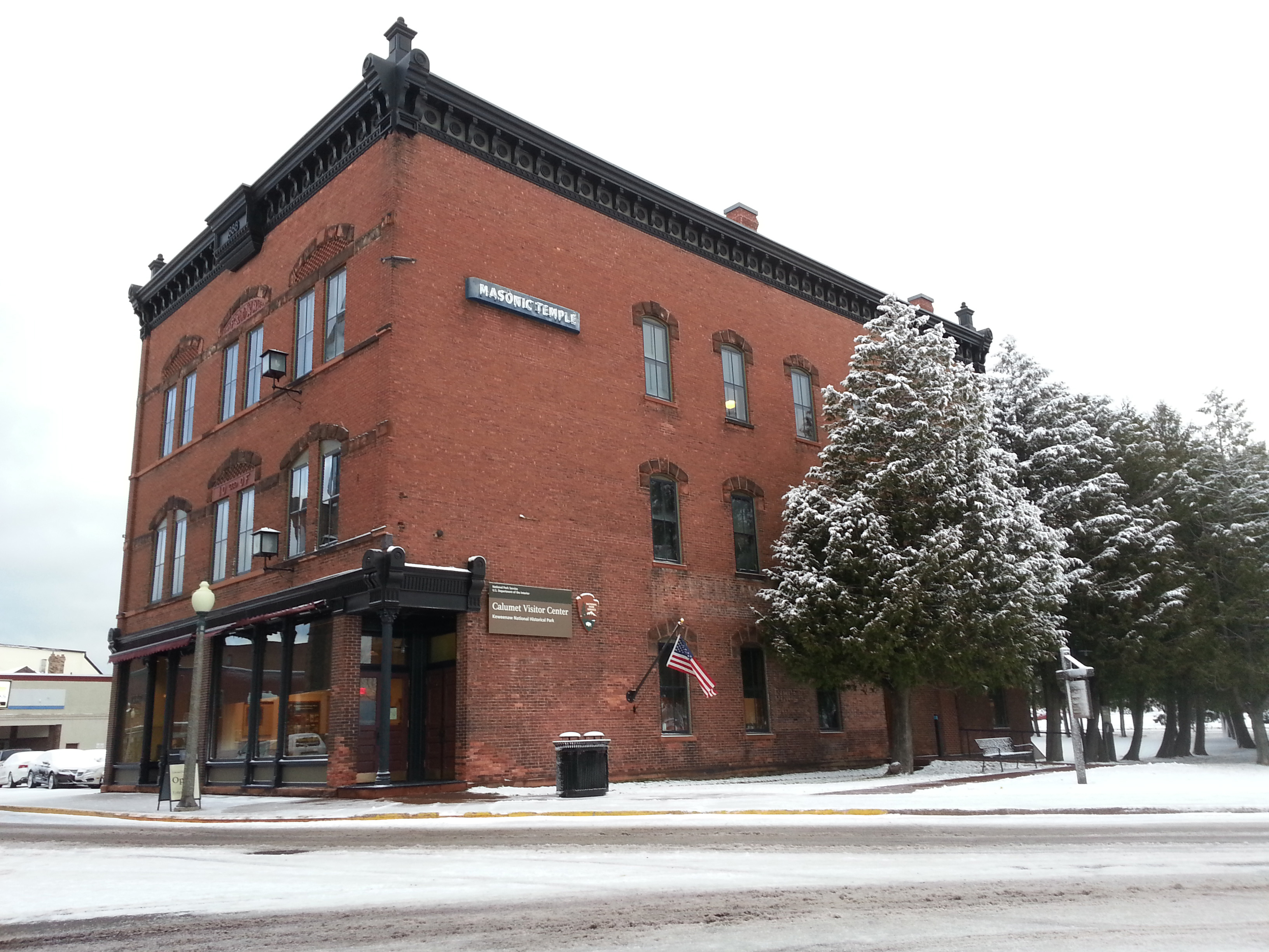Three story brick building, with snow covered trees along the right side