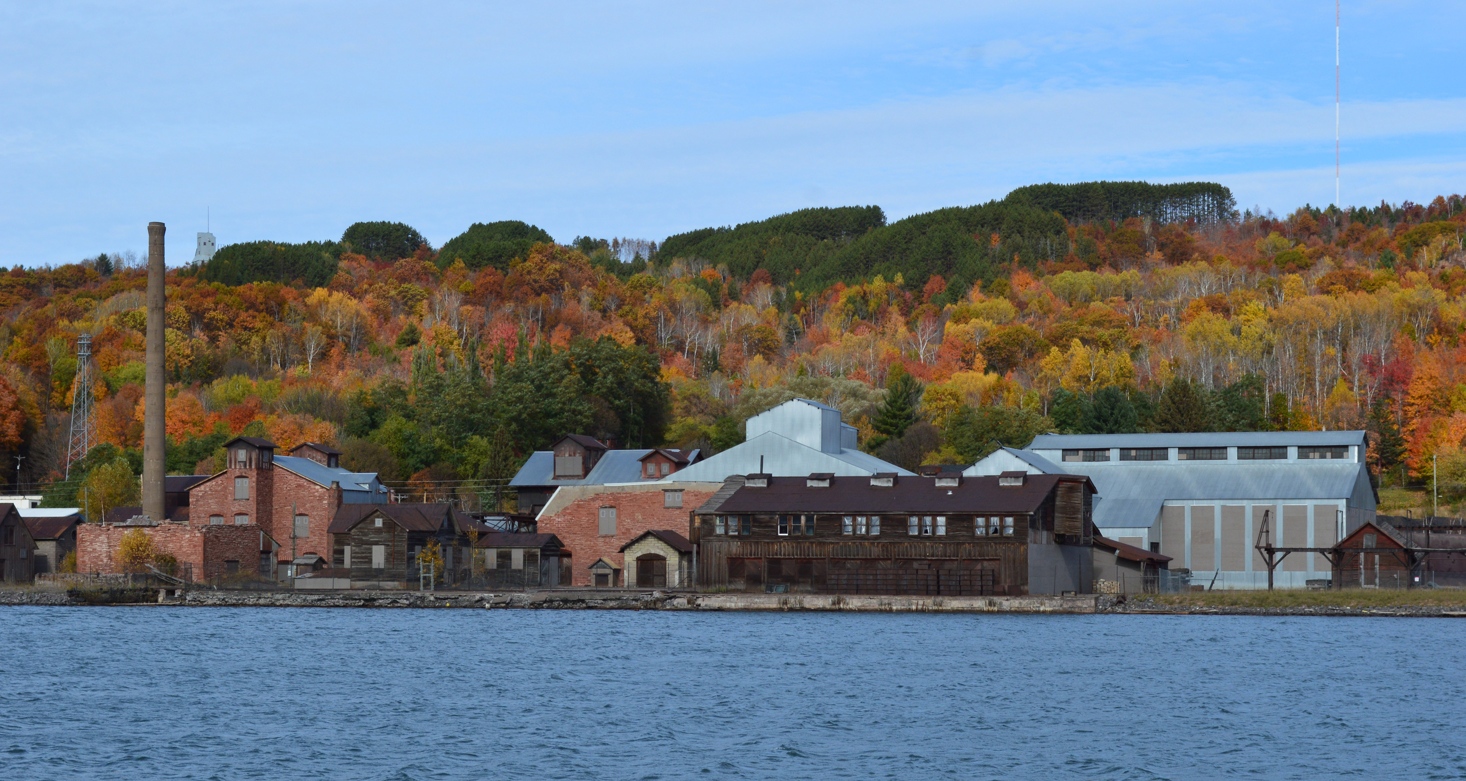 With a colorful autumn background, numerous industrial buildings sit on the waterfront