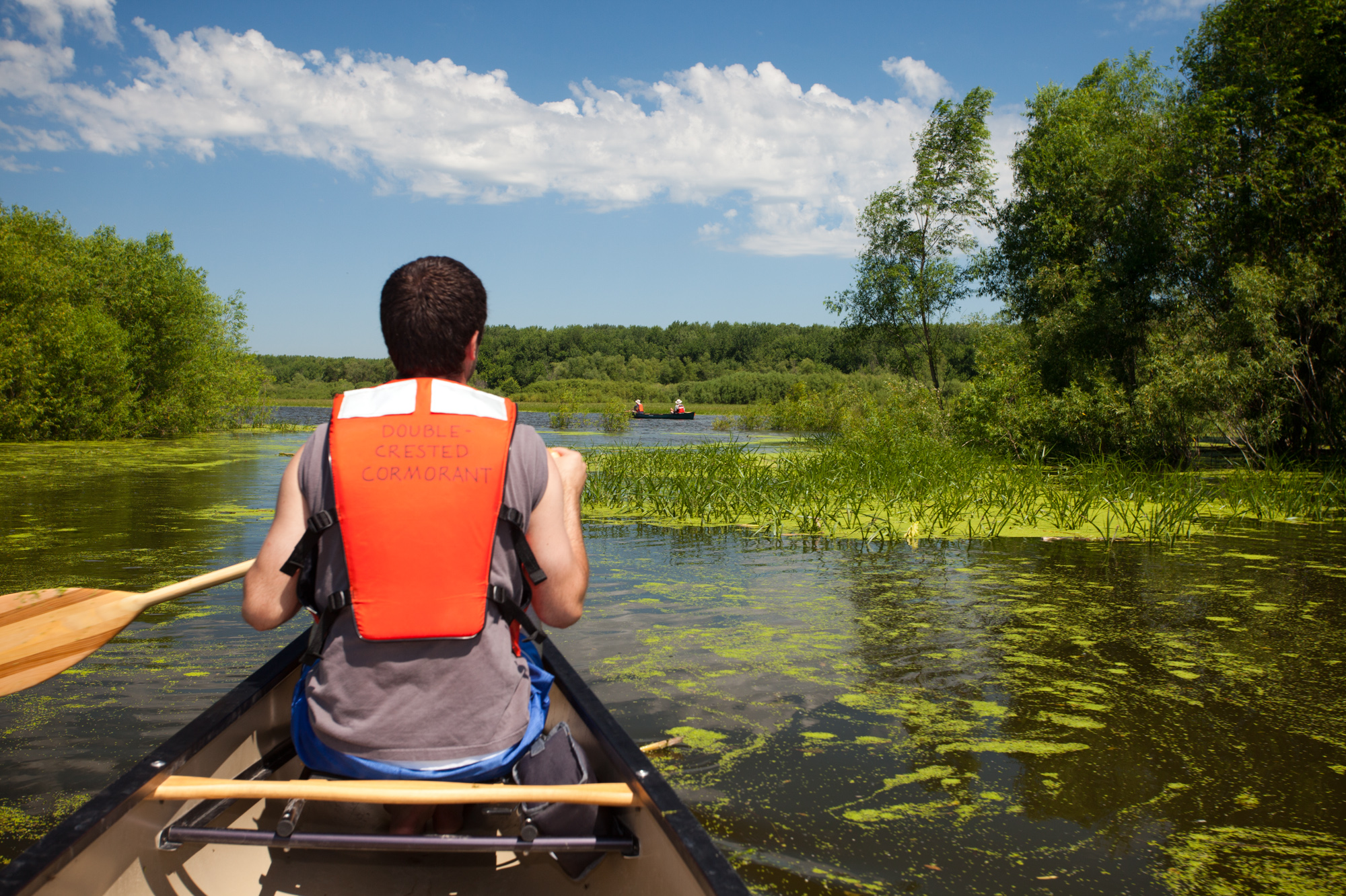 A canoeist paddles through a water channel between islands.