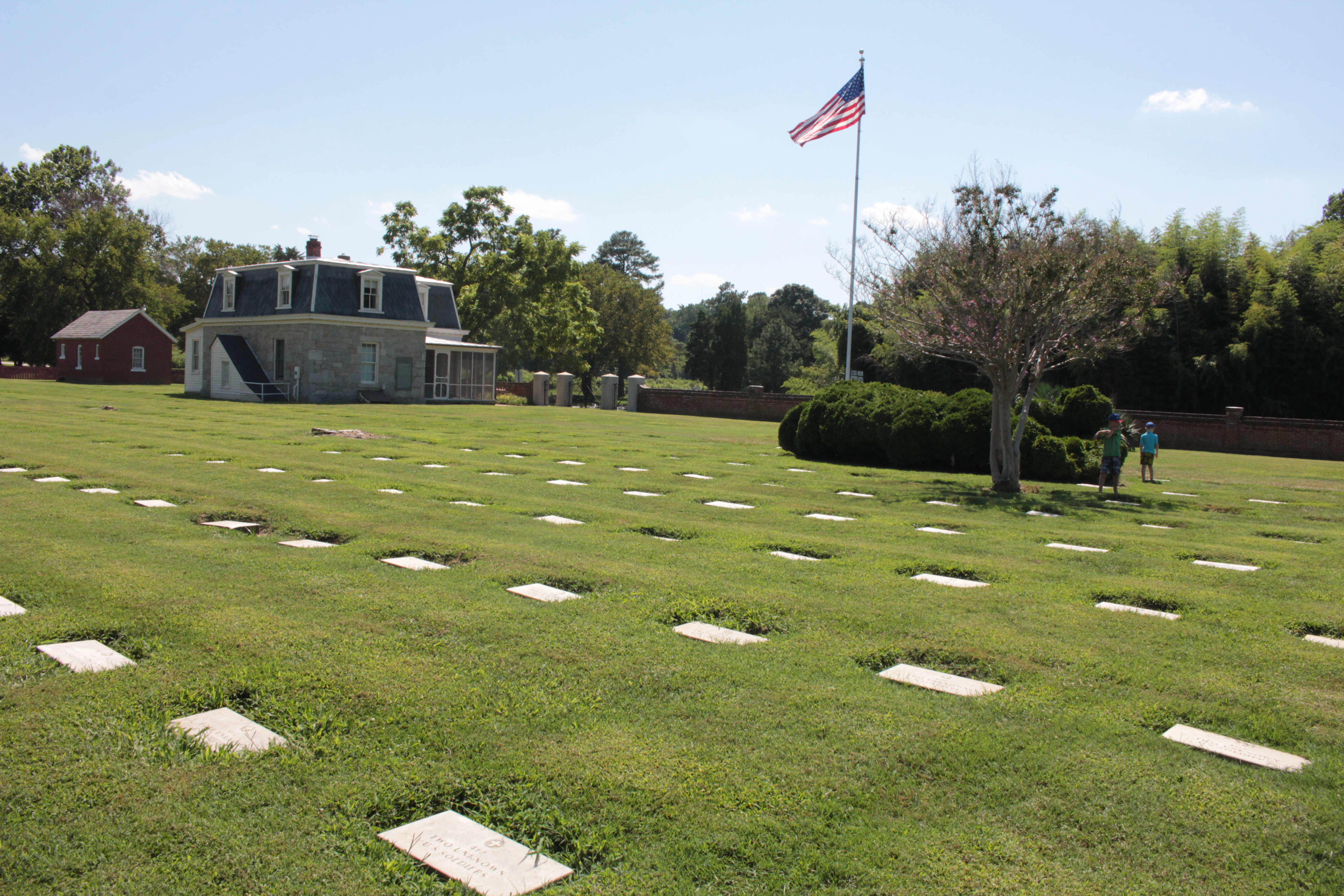 National Cemetery showing tombstones, American Flag and Cemetery Lodge in sunlight.