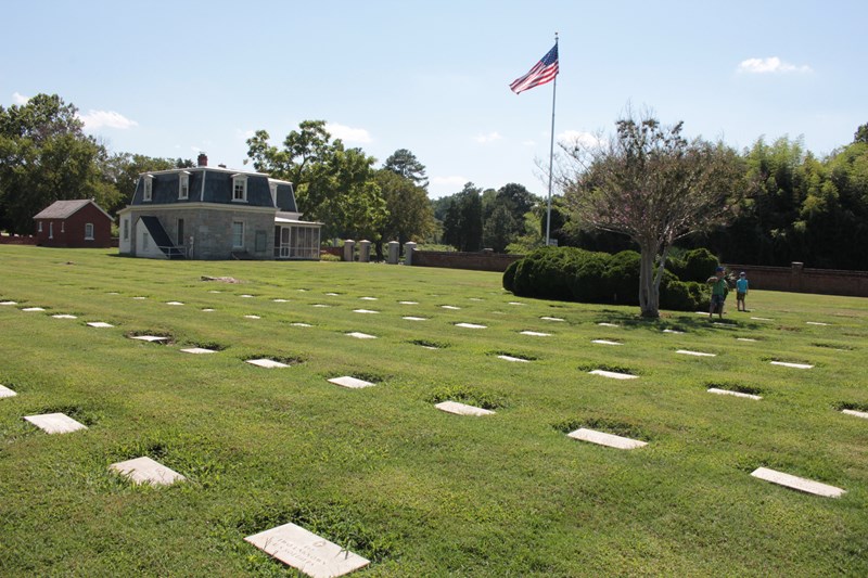 National Cemetery National Cemetery showing tombstones, American Flag and Cemetery Lodge in sunlight.