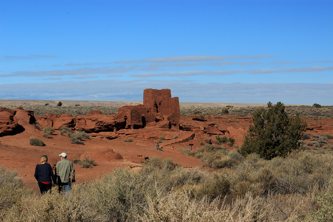 a man and woman walking toward a three-story sandstone tower