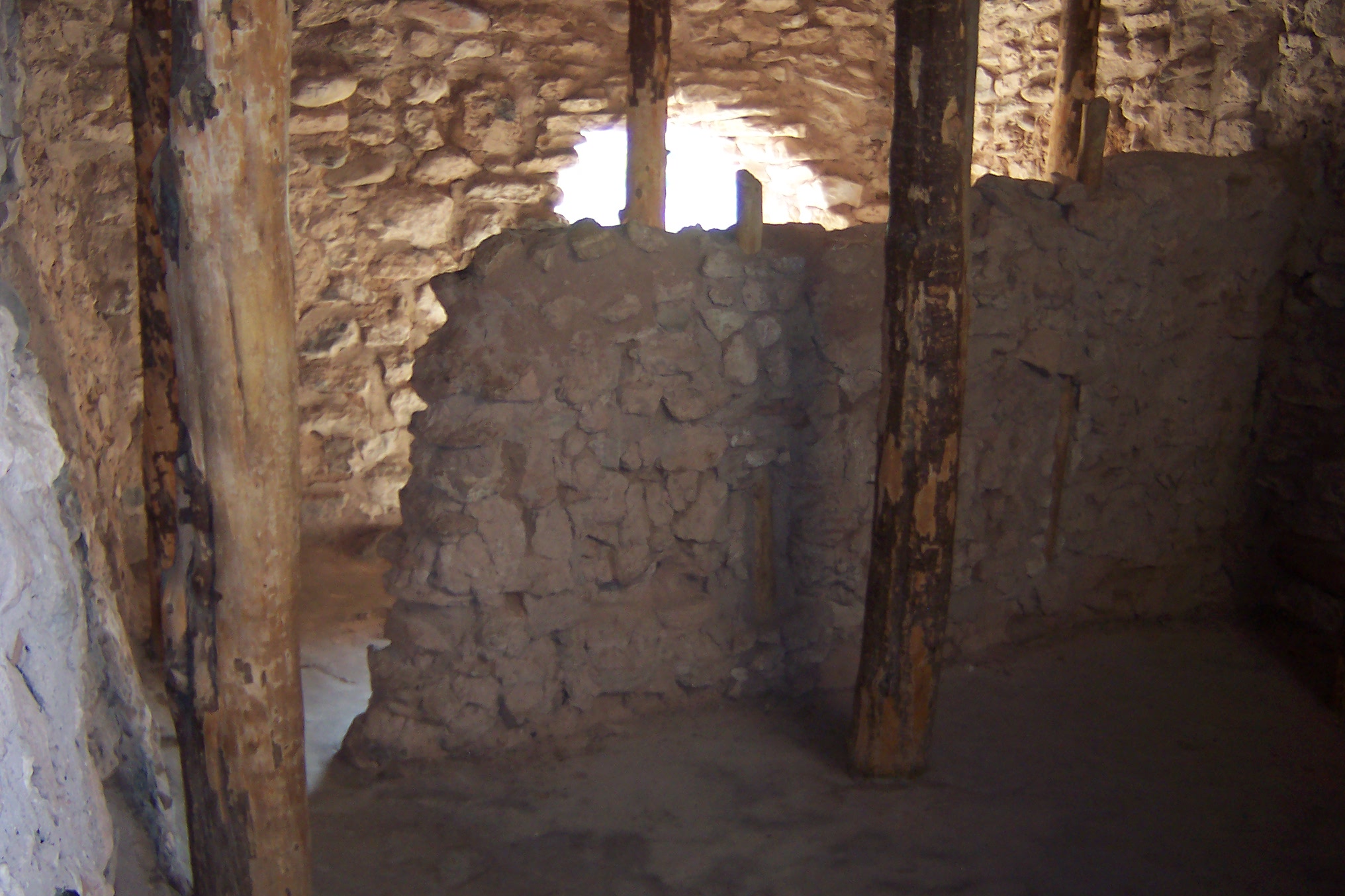 The inside of a masonry room with wood posts supporting the roof.