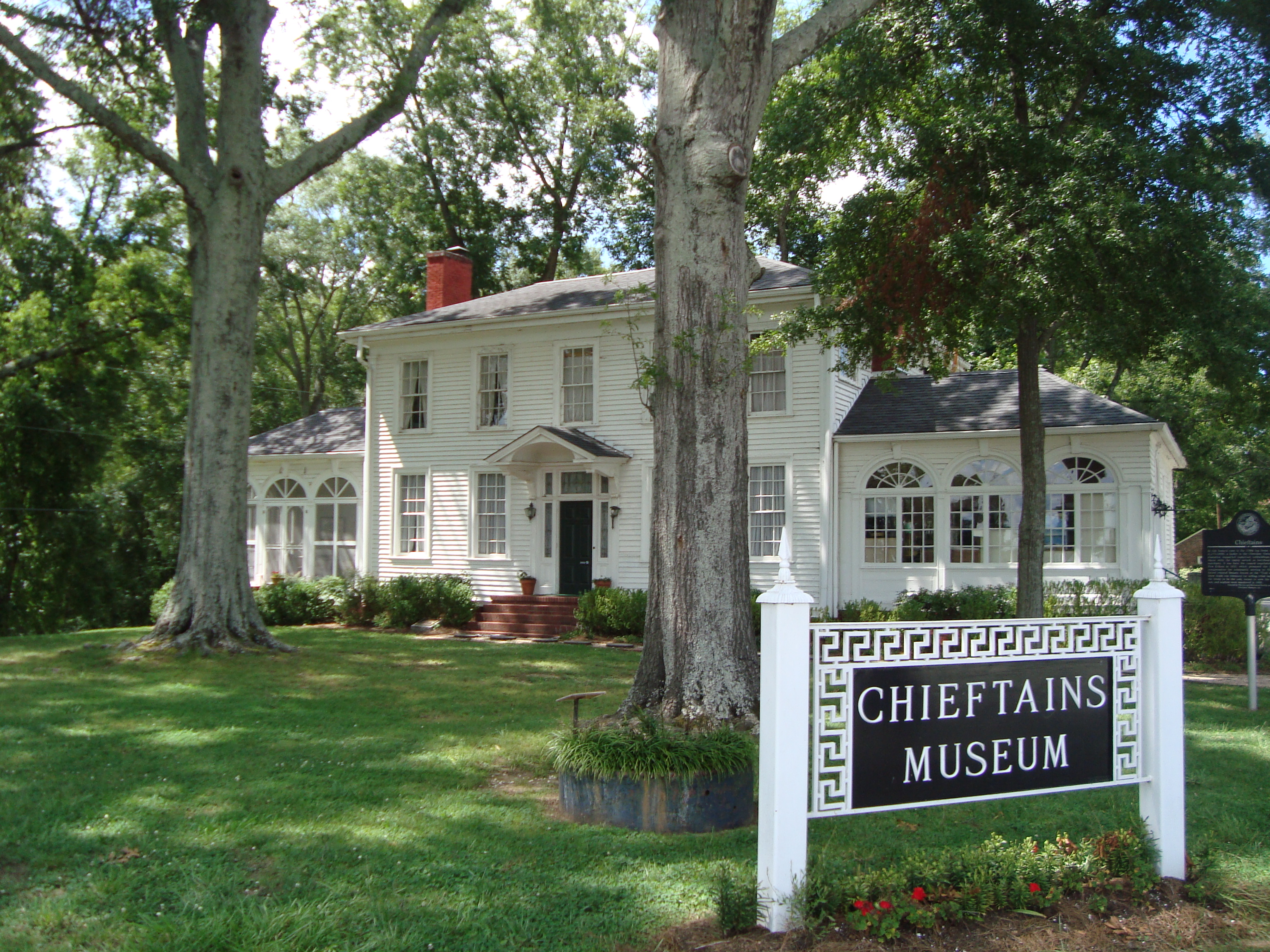 large white house, green lawn, two trees in front