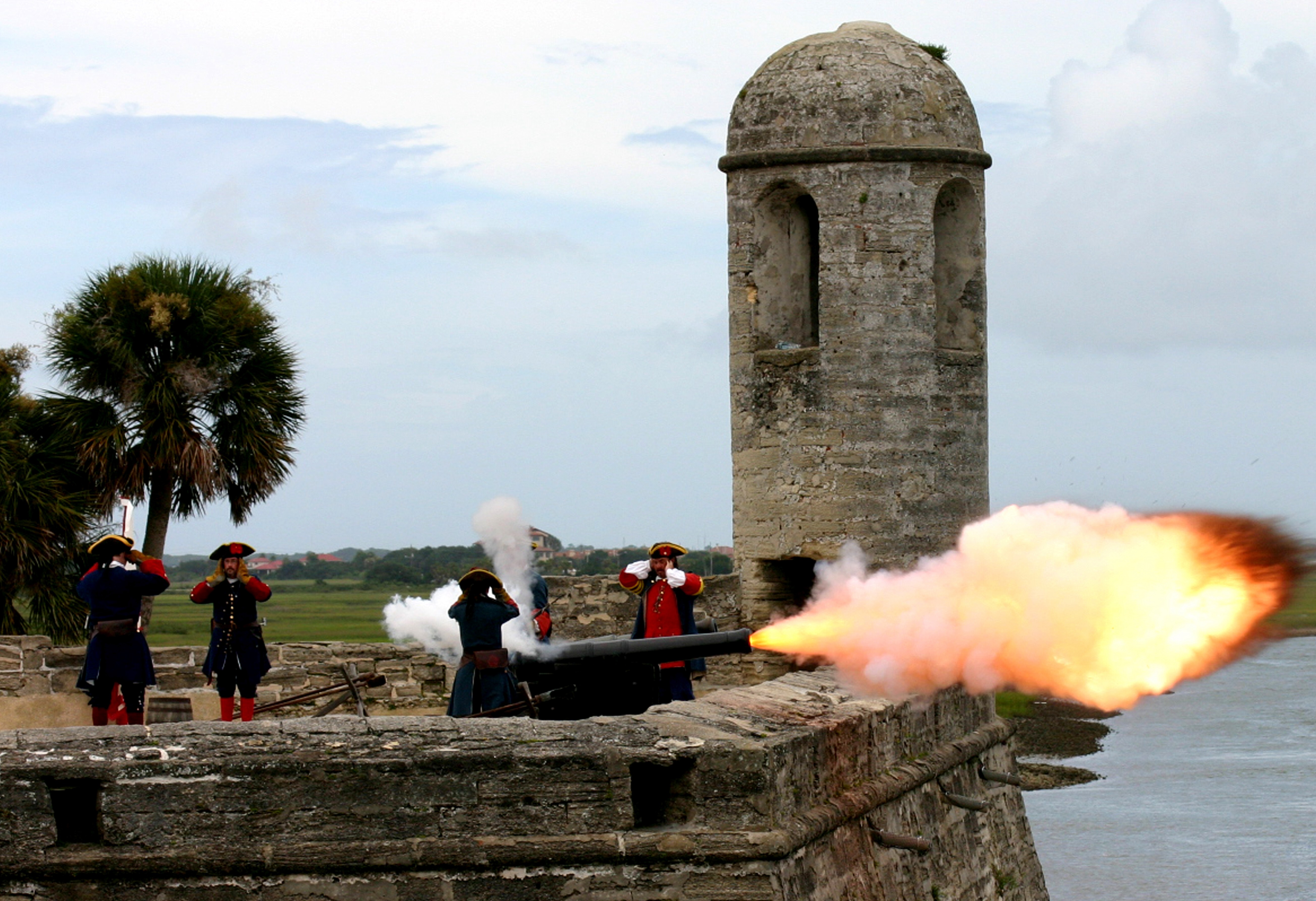 Re-enactors of the first Spanish period cover their ears while firing a cannon.