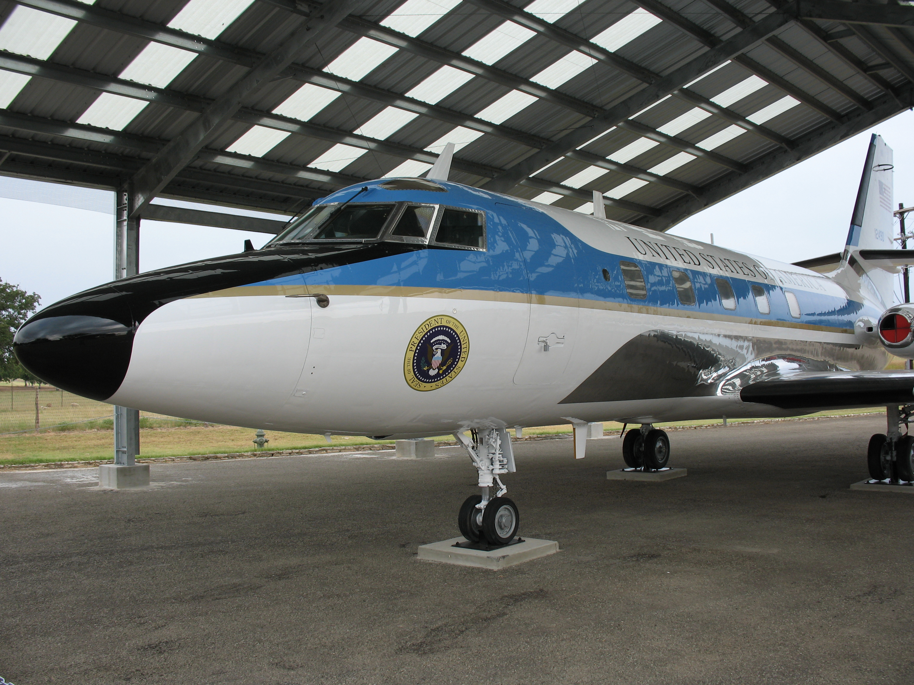 An exterior view of a White and blue jet with presidential seal painted just below the cockpit.