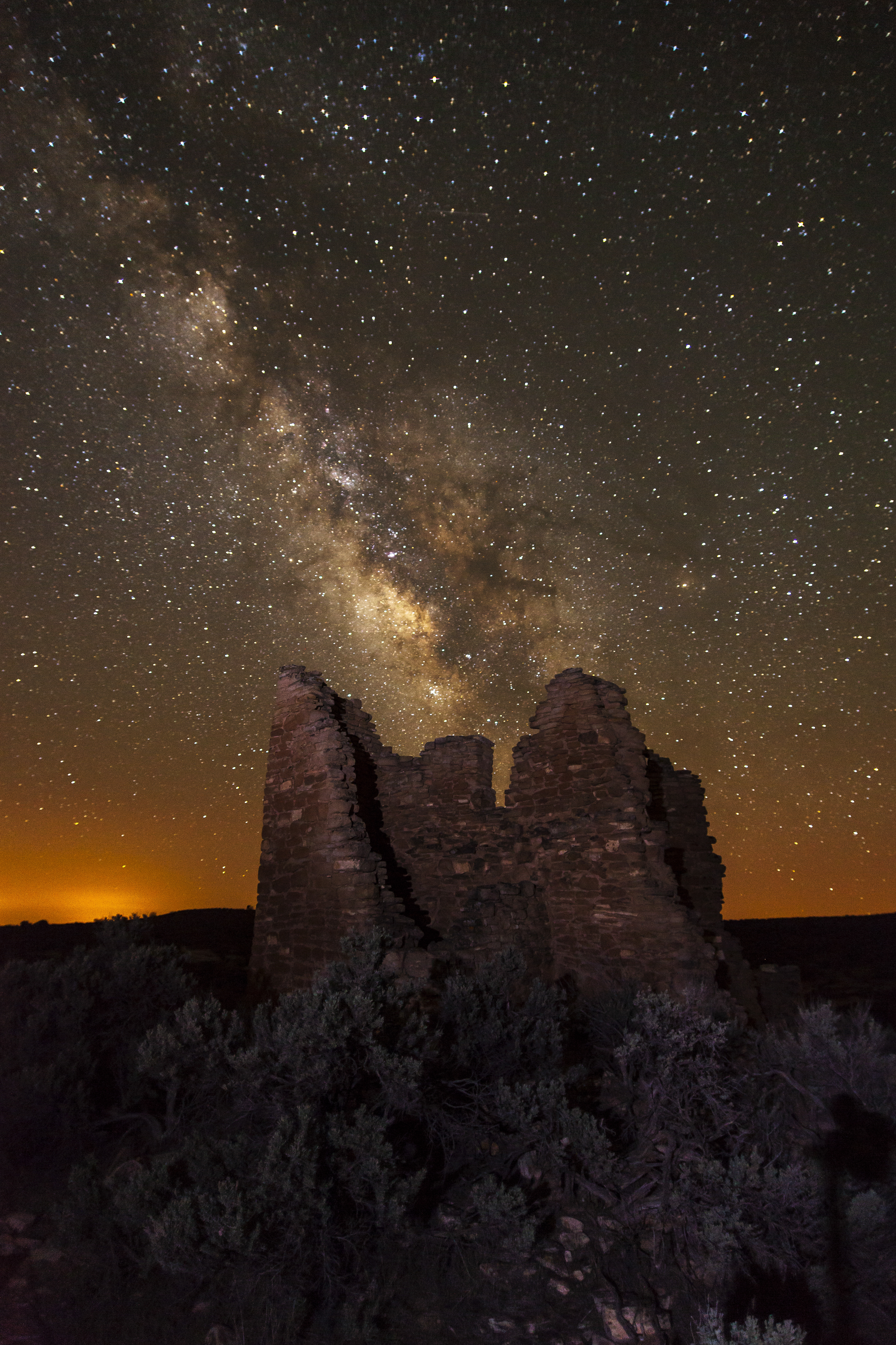 a stone structure at night with the Milky Way arcing overhead