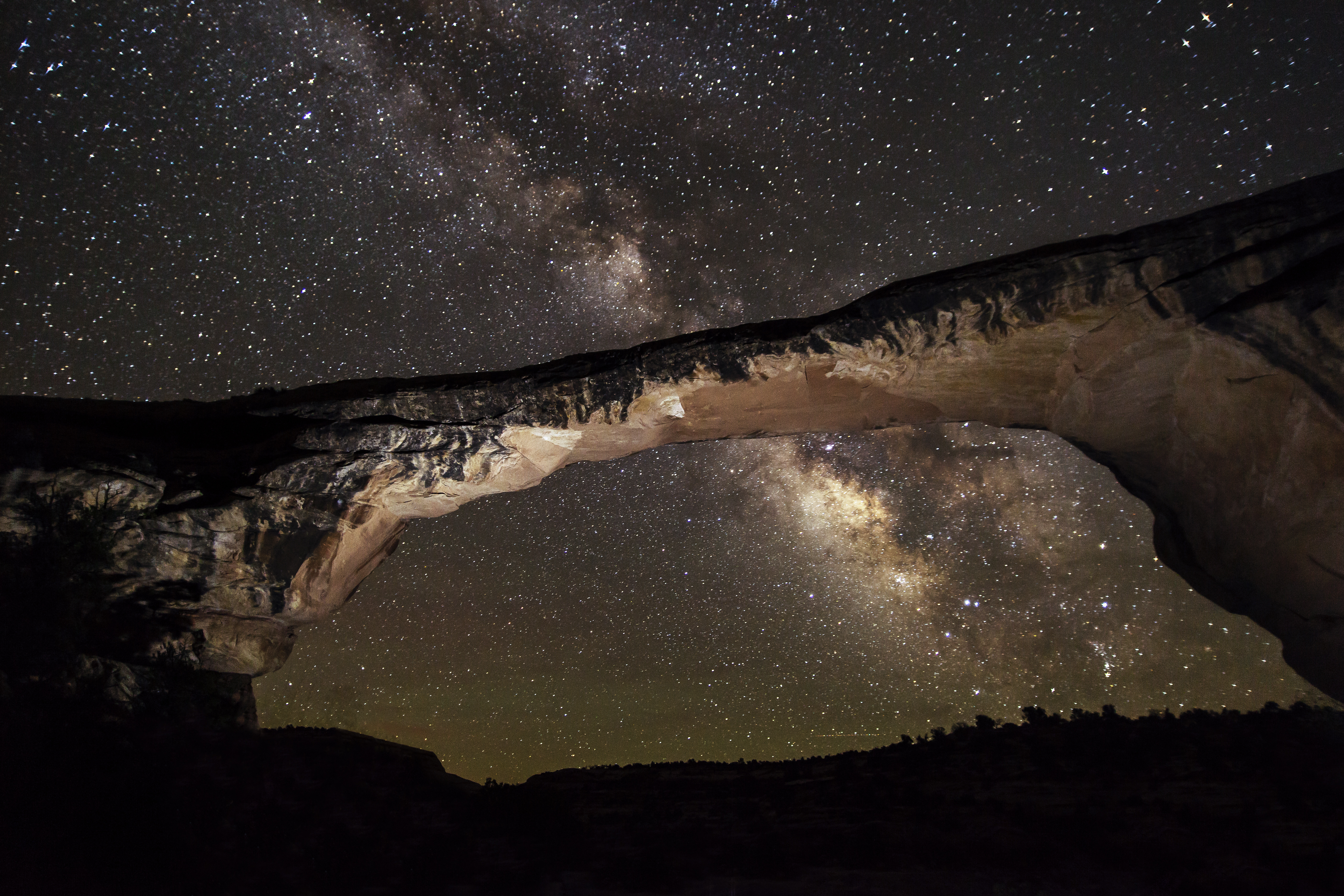 a natural bridge at night with the Milky Way arcing overhead
