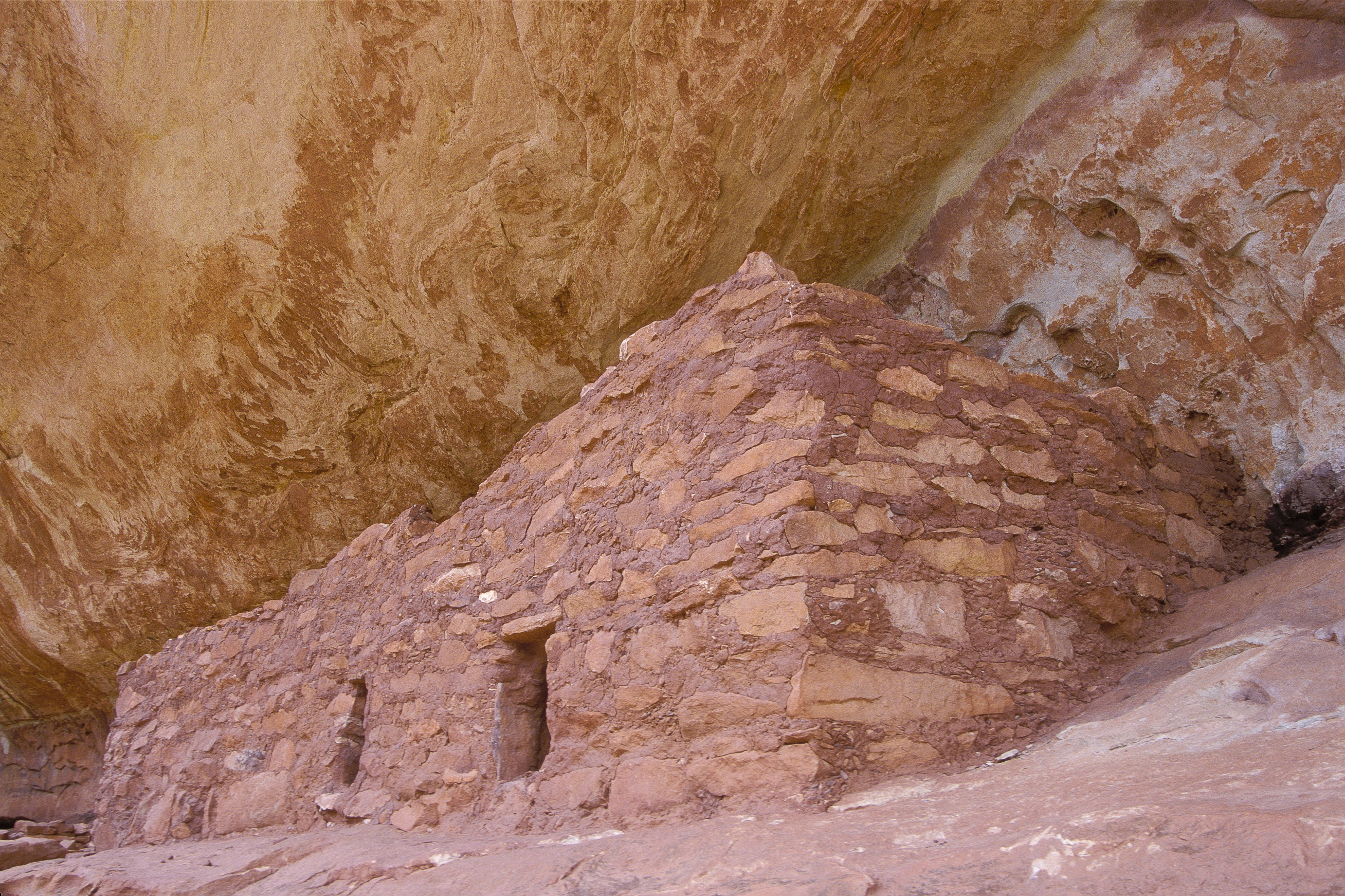 a stone structure below a rock alcove