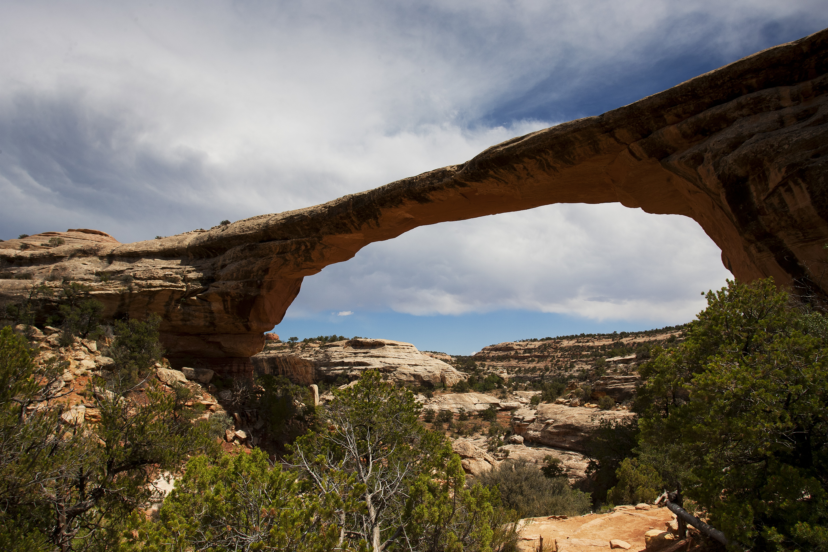 a broad natural bridge with clouds in the sky
