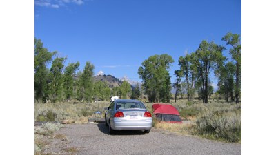 Gros Ventre campsite with red tent and silver sedan surrounded by sagebrush and cottonwoods