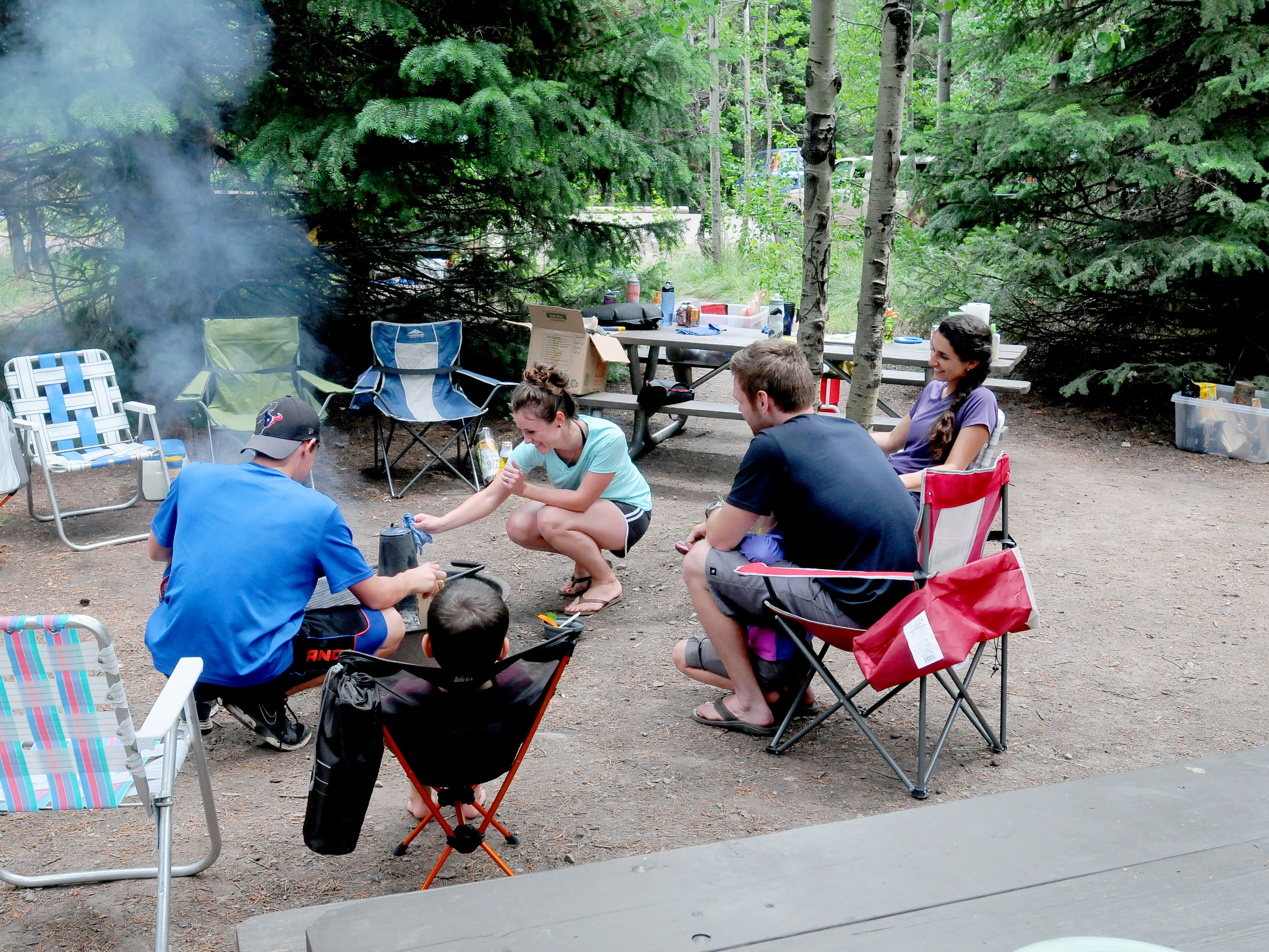 five campers around campfire at campsite