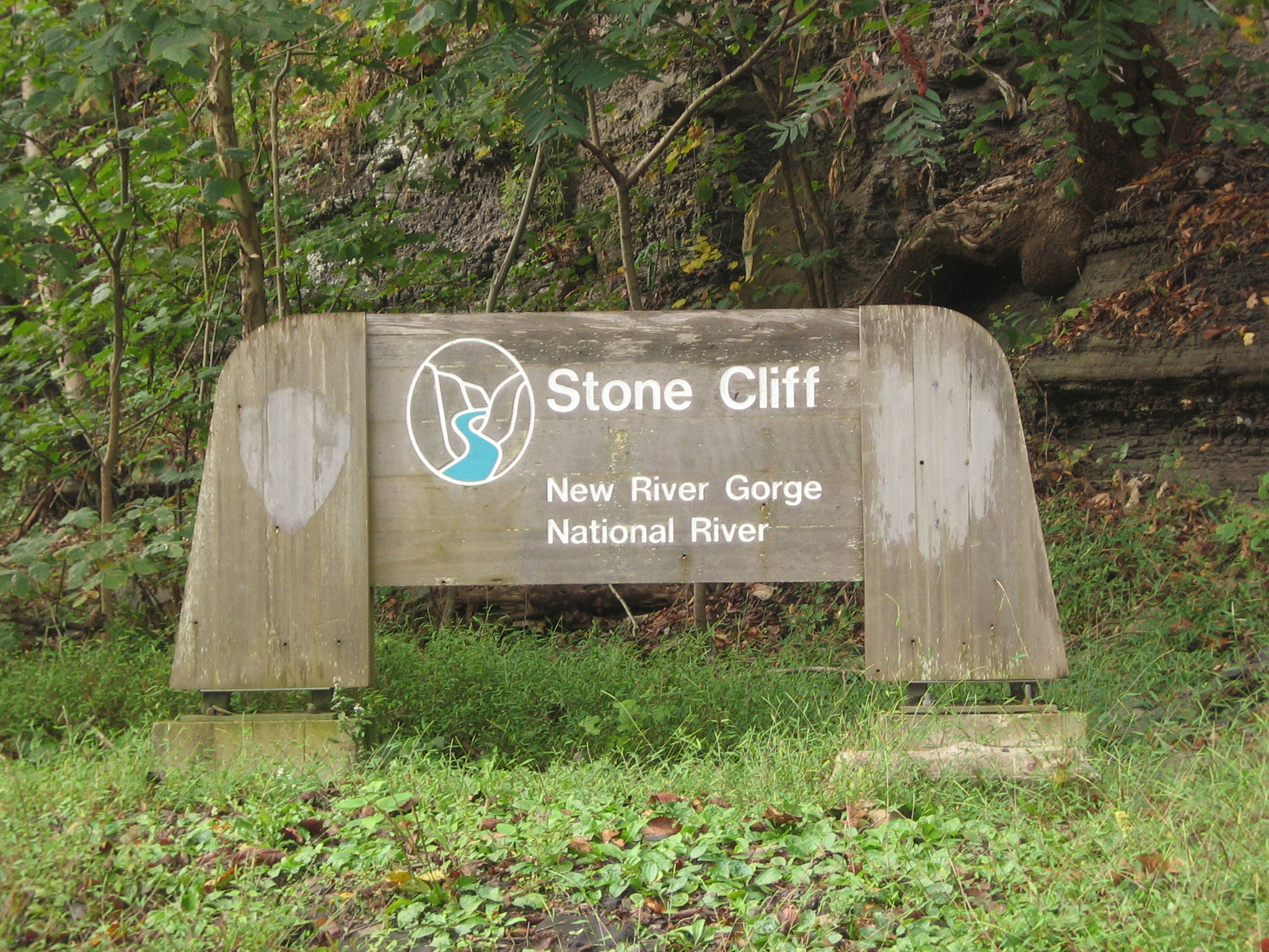 A brown sign with a drawing of a river on it that says Stone Cliff on it