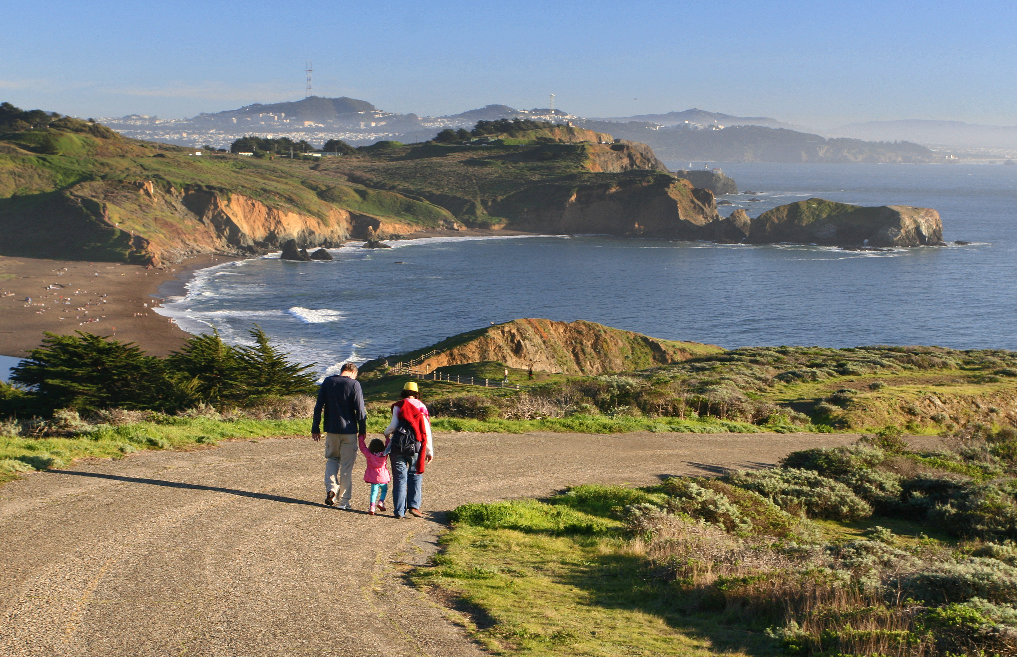 View south with family on road in foreground and Rodeo Beach and cove in front of Point Bonita.