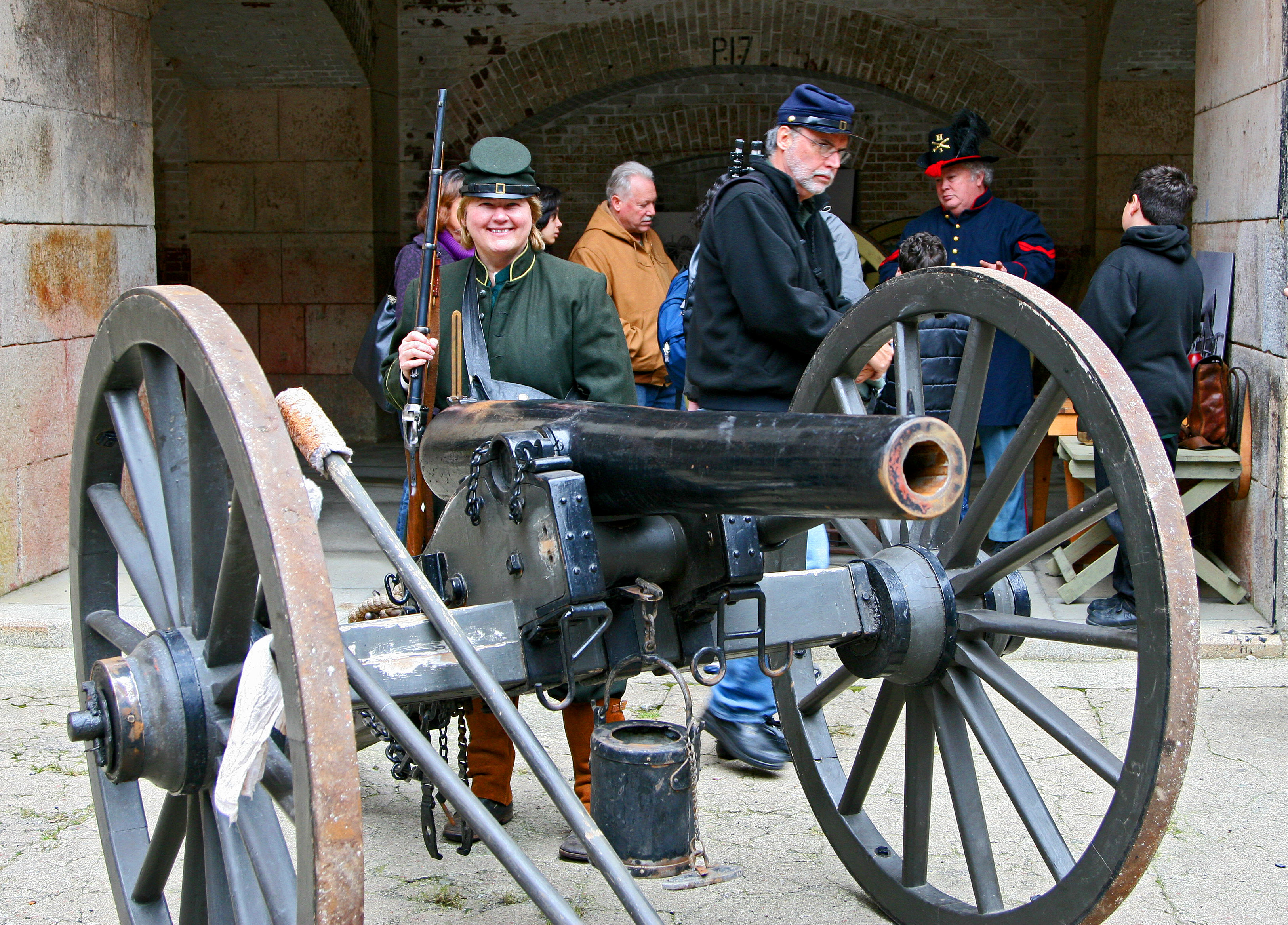 A cannon stands in front of Civil War re-enactors talking to the public.