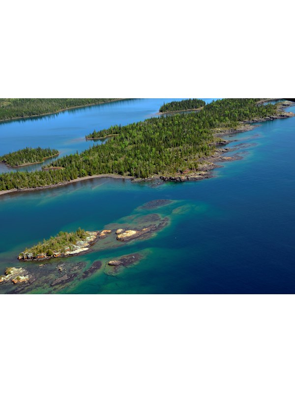 Aerial view of West Caribou Island surrounded by the blue waters of Lake Superior.