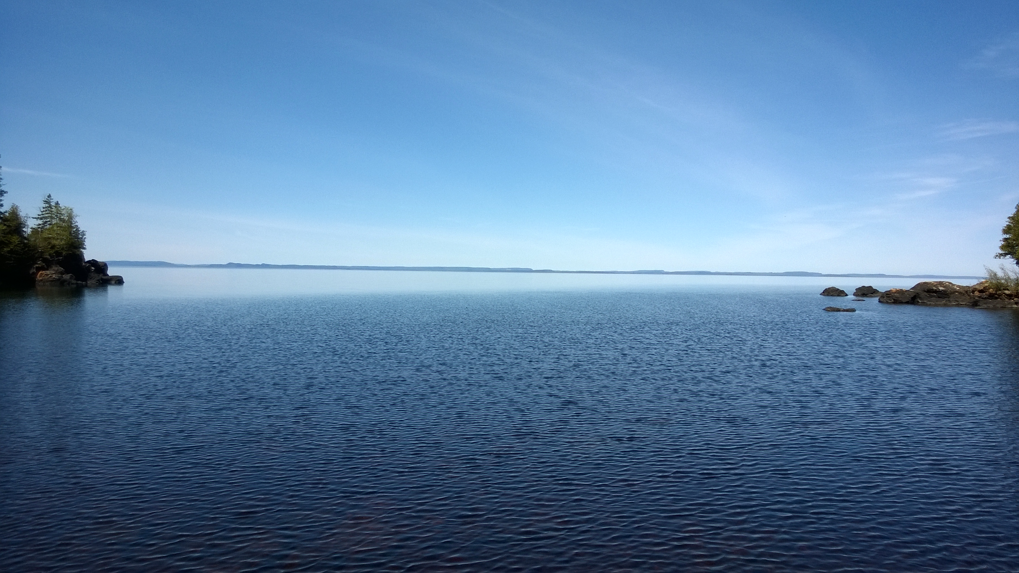 View of the blue waters of Hugunnin Cove with the shoreline of Canada in the distance.