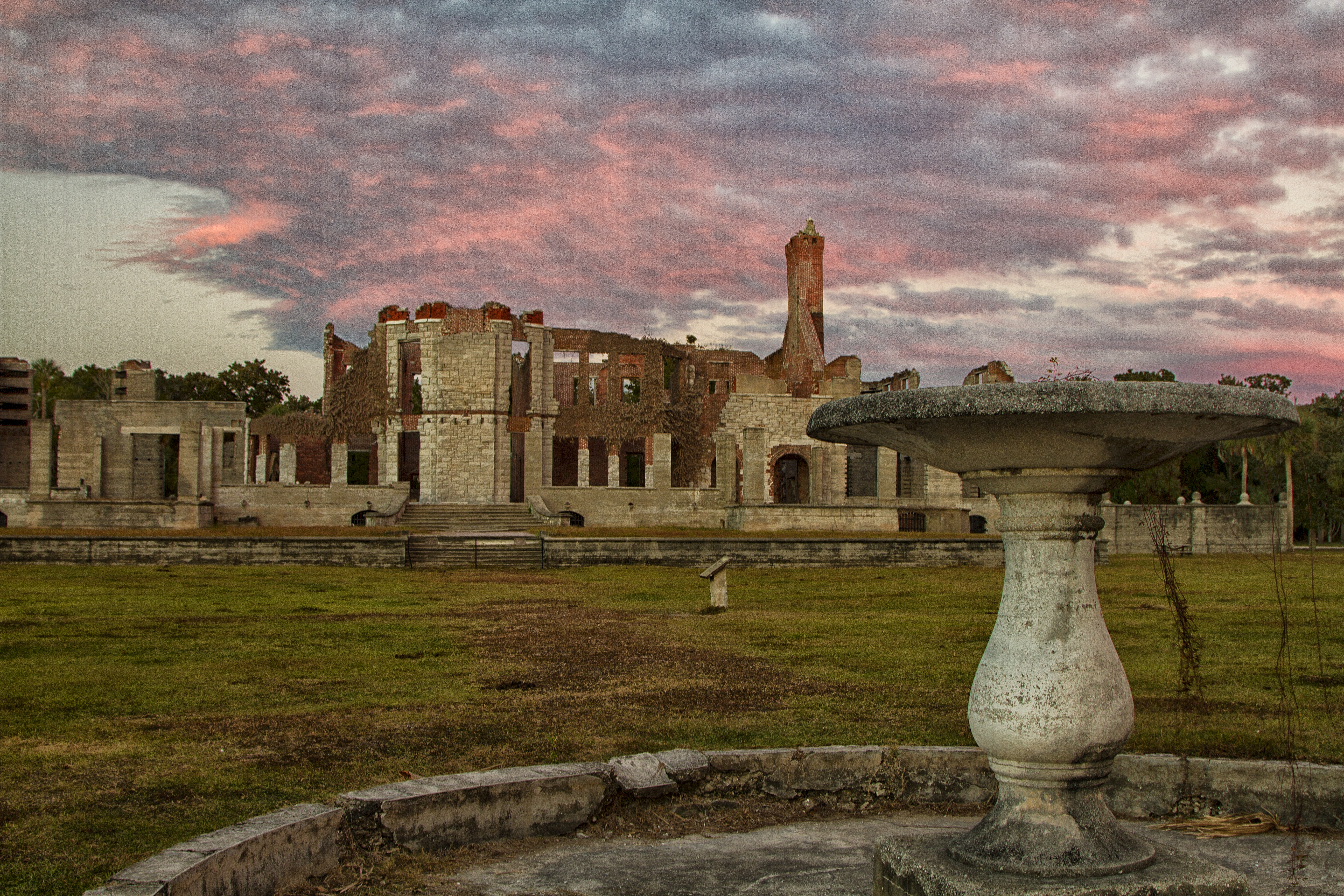 brick and stone ruins of a large mansion at sunset under colorful clouds