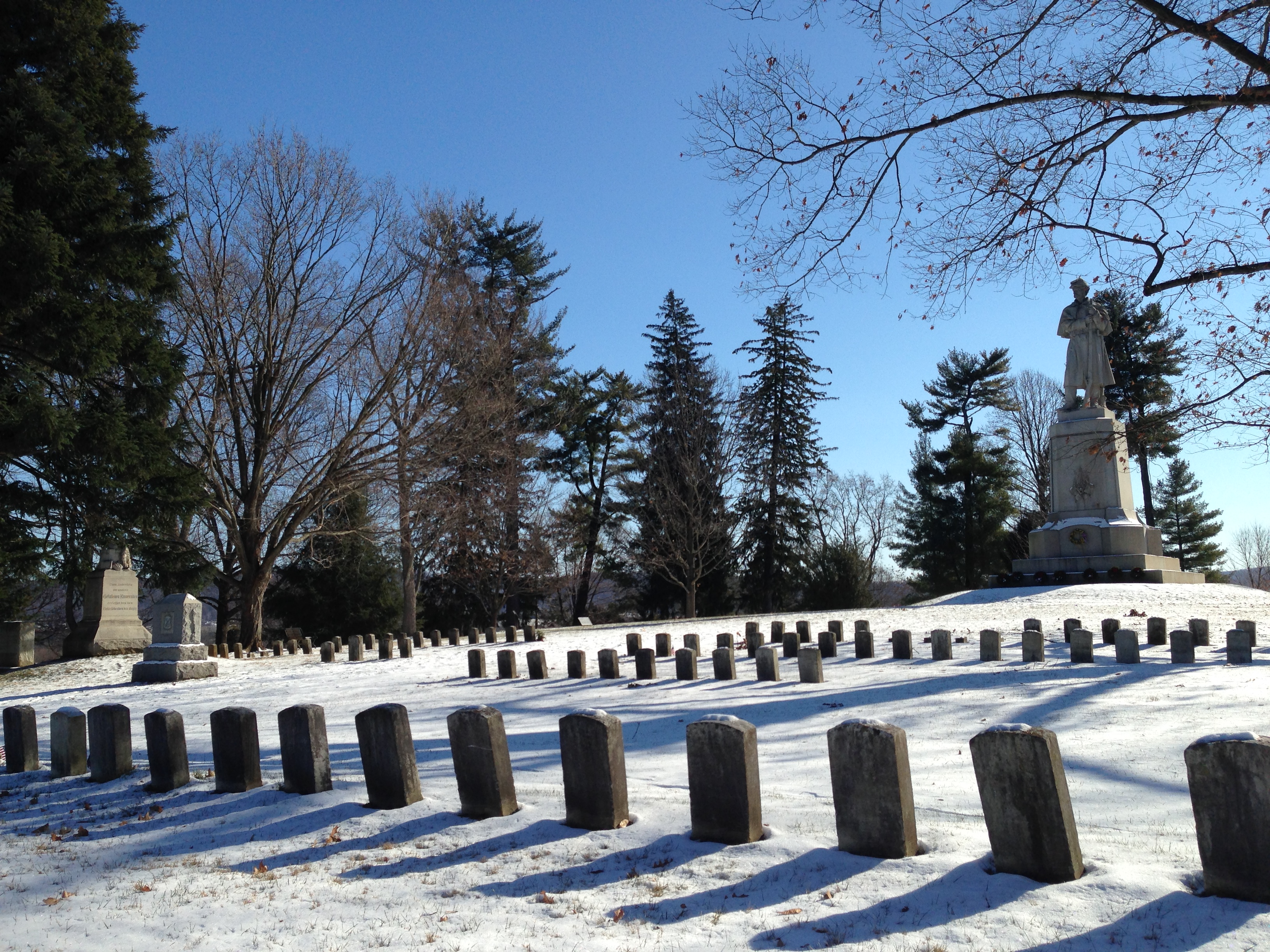 a monument of a soldier in the background with graves in front of the monument
