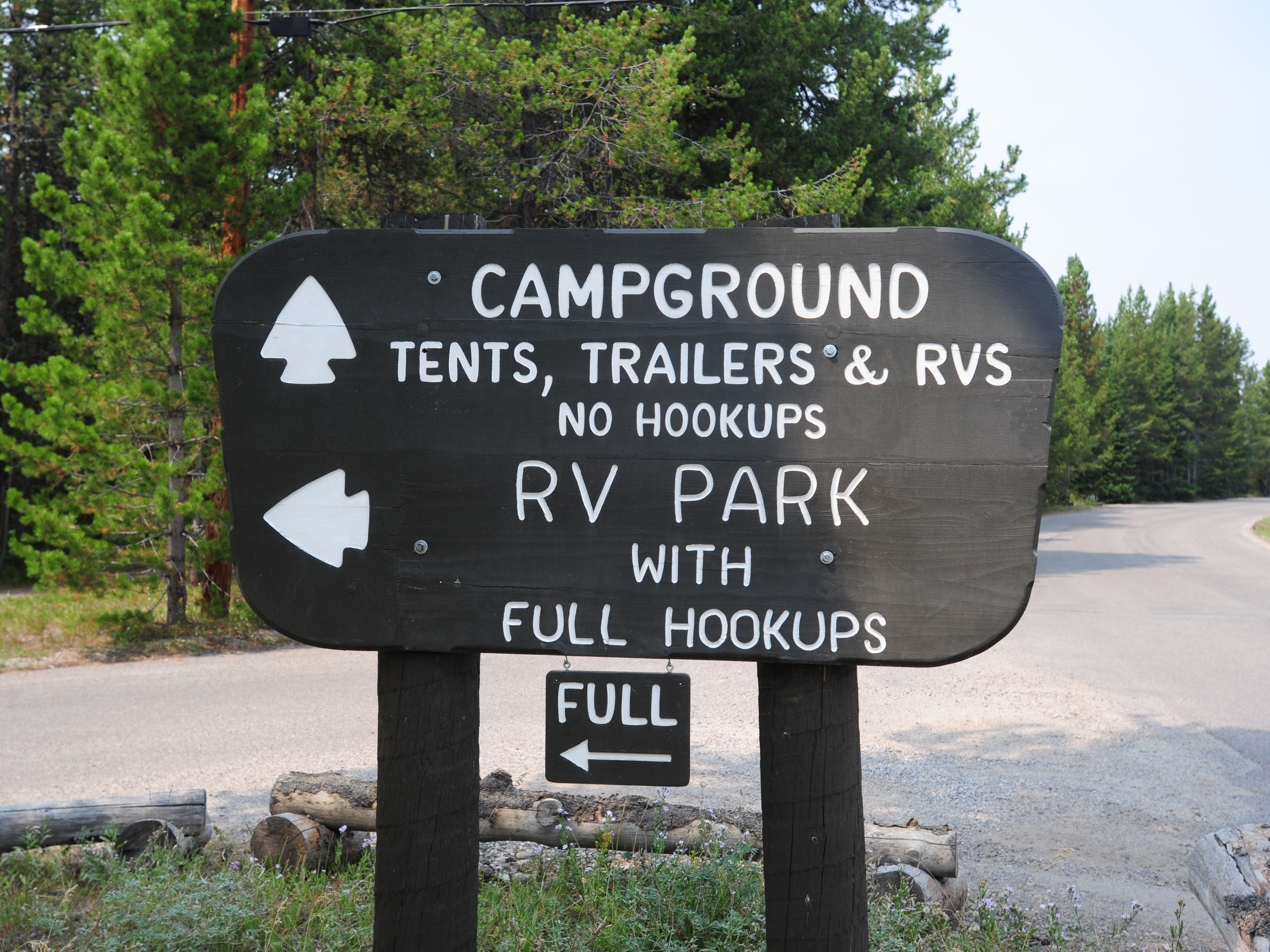Brown wooden park service sign with campground information and RV park information