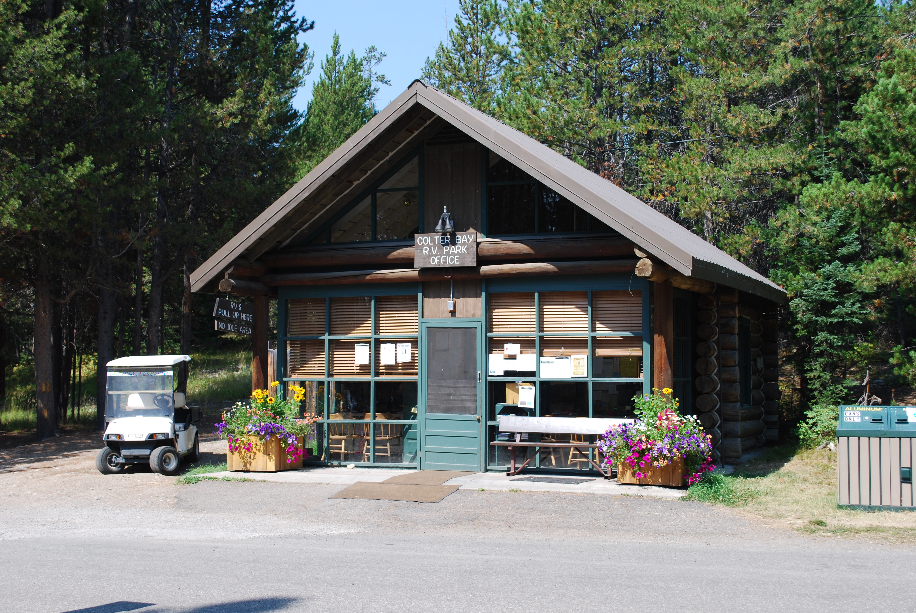 RV park brown log cabin with green door and flowers in barrels