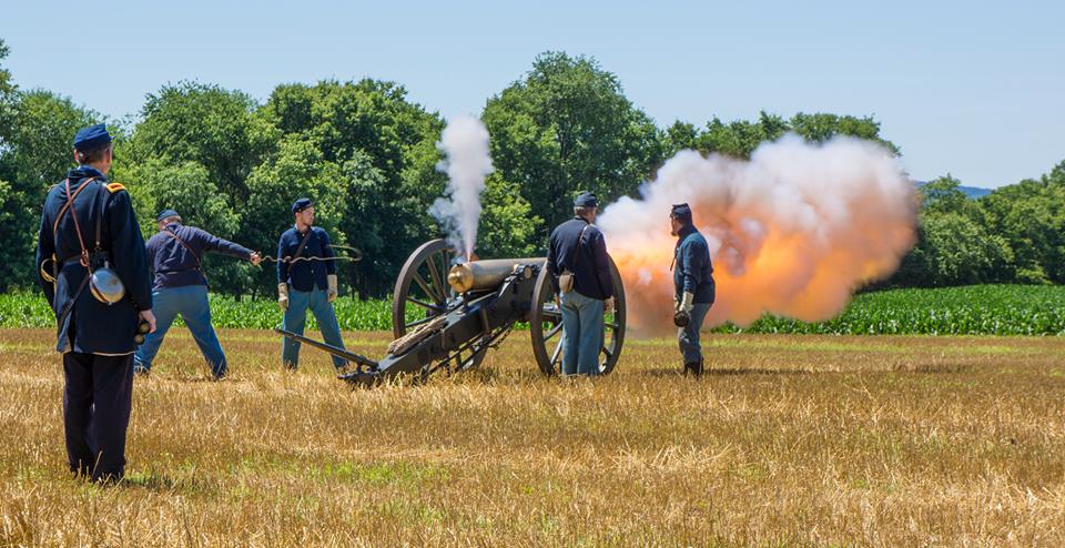 Smoke and fire erupt from an artillery piece as it is fired by Union soldiers.
